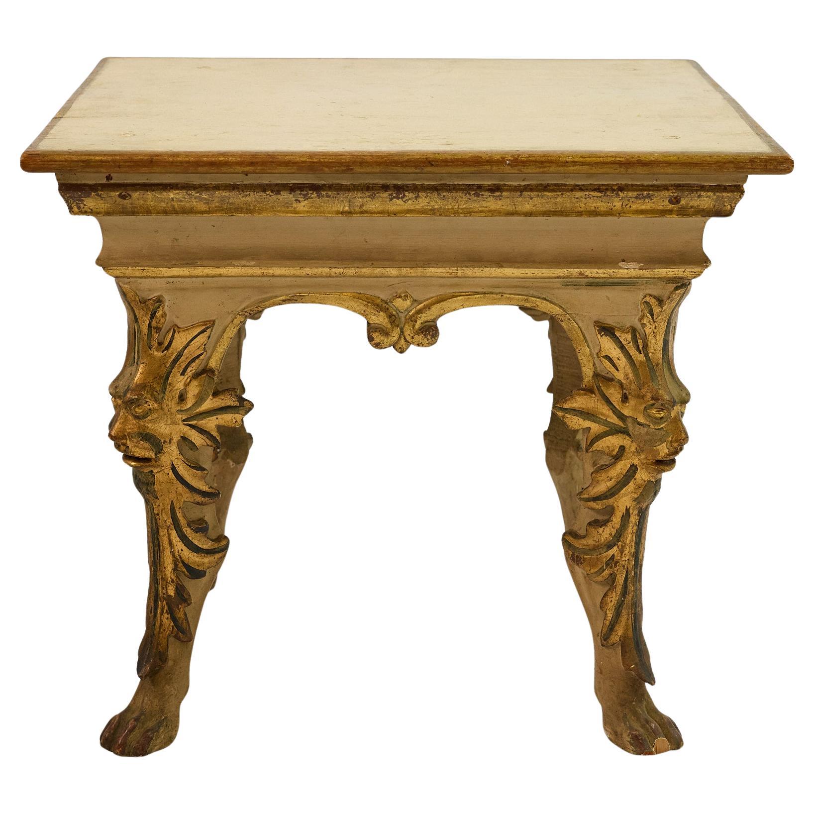 Fabulous Italian side table slightly off-square in shape and beautifully hand carved in the Baroque aesthetic. The table is painted cream with gold leaf accents all over. The table top steps down to a scrolled apron with double arches and striking