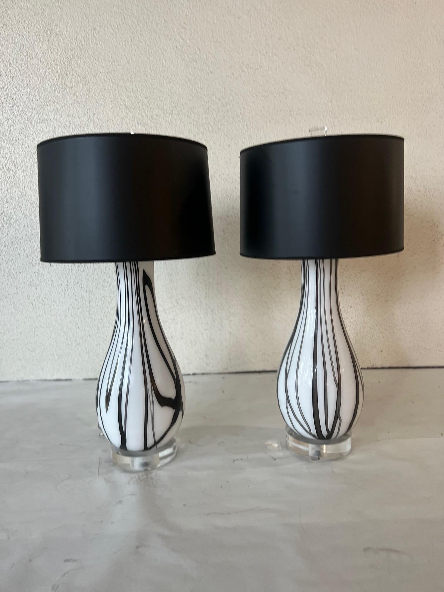 A pair of custom venetian glass lamps in black and white with blacks shades trimmed in silver.