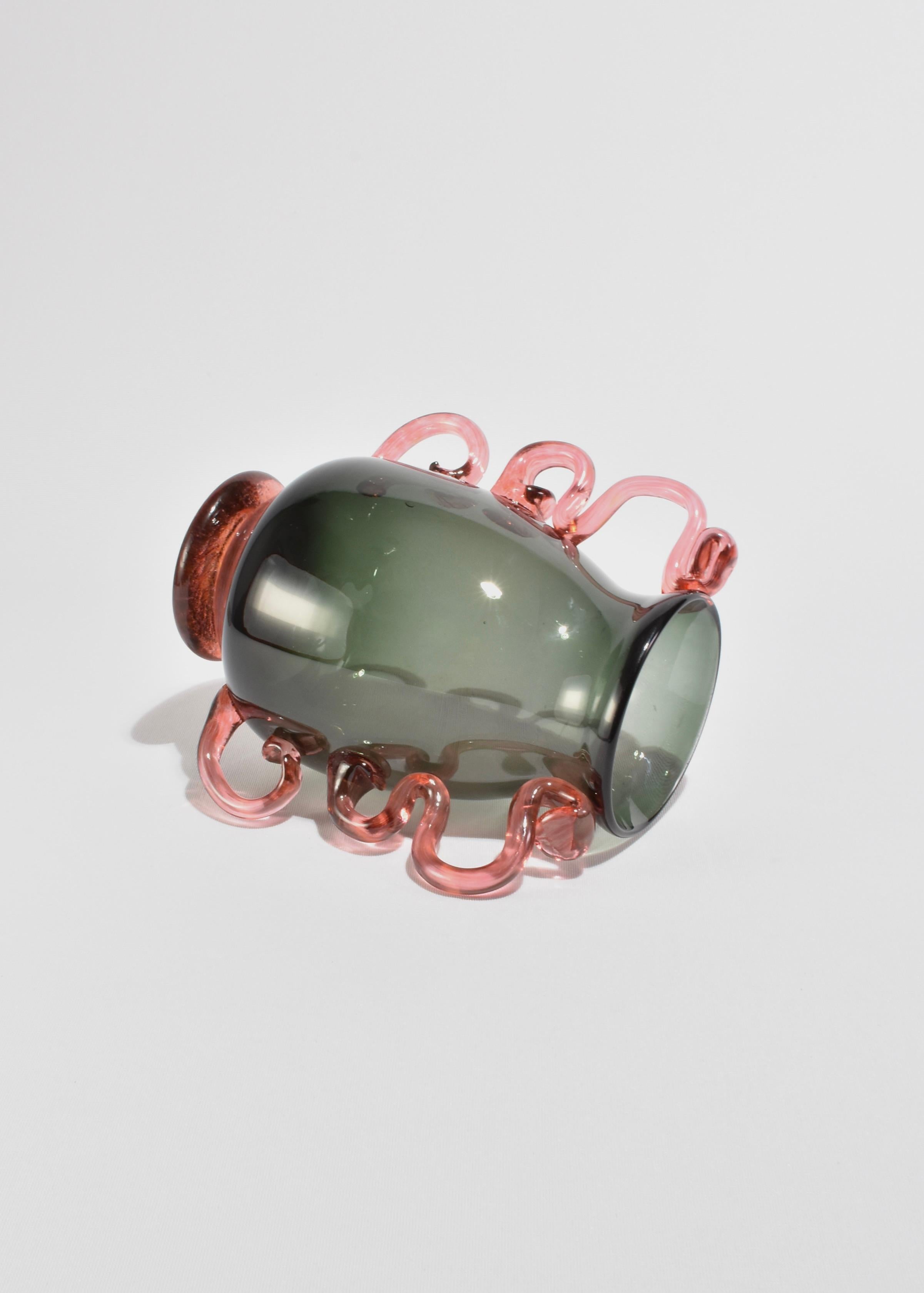Nuestro jarrón de inspiración veneciana presenta una forma gris redondeada complementada con asas onduladas de color rosa. Este jarrón, que forma parte de nuestra nueva colección interna, combina tonos modernos con una forma inspirada en la