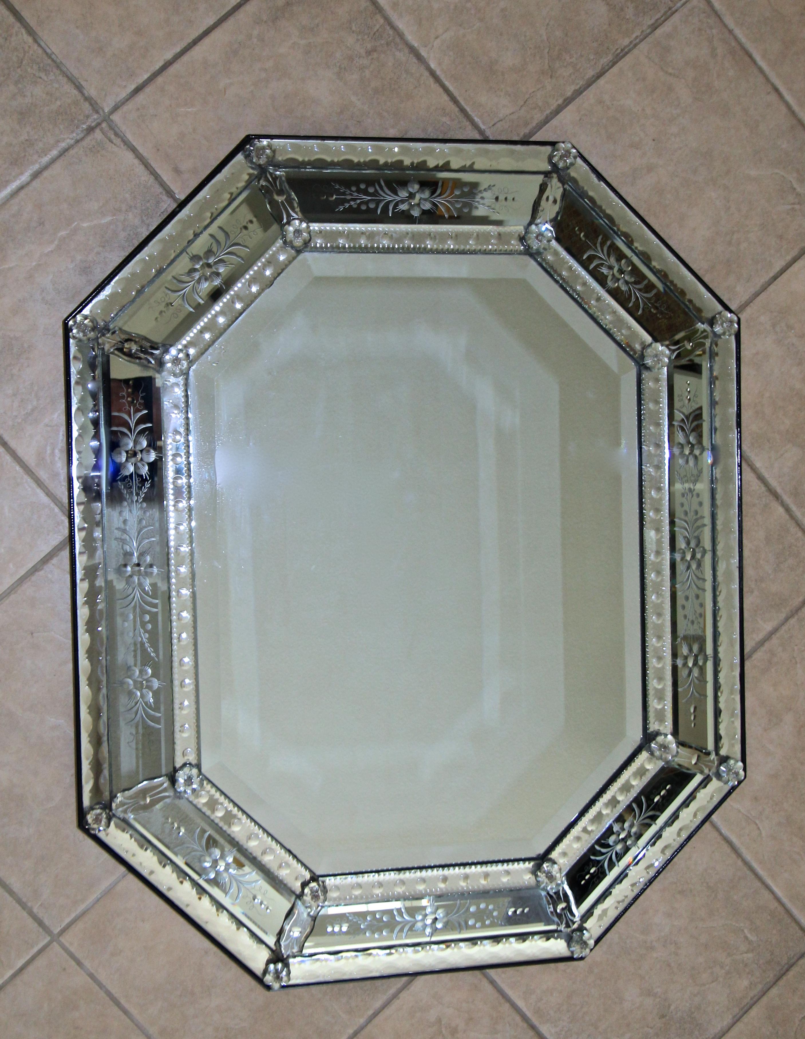 Very attractive 1940s octagonal Venetian Italian etched wall mirror. The mirror is expertly handcrafted revealing numerous intricate etched flower and scroll motif threw out. The large inner mirror is beveled, the outer panels have lots of finely