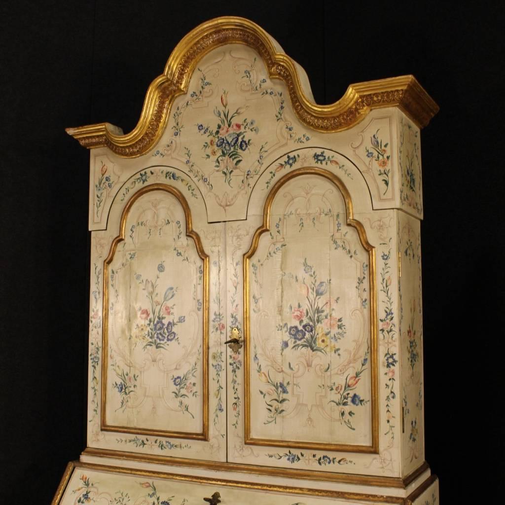 Spectacular Venetian trumeau from the mid-20th century. Furniture in ornately carved, lacquered, gilded and hand-painted wood with floral decorations. Lounge trumeau fitted with three external drawers, fall-front and two doors in the upper body.