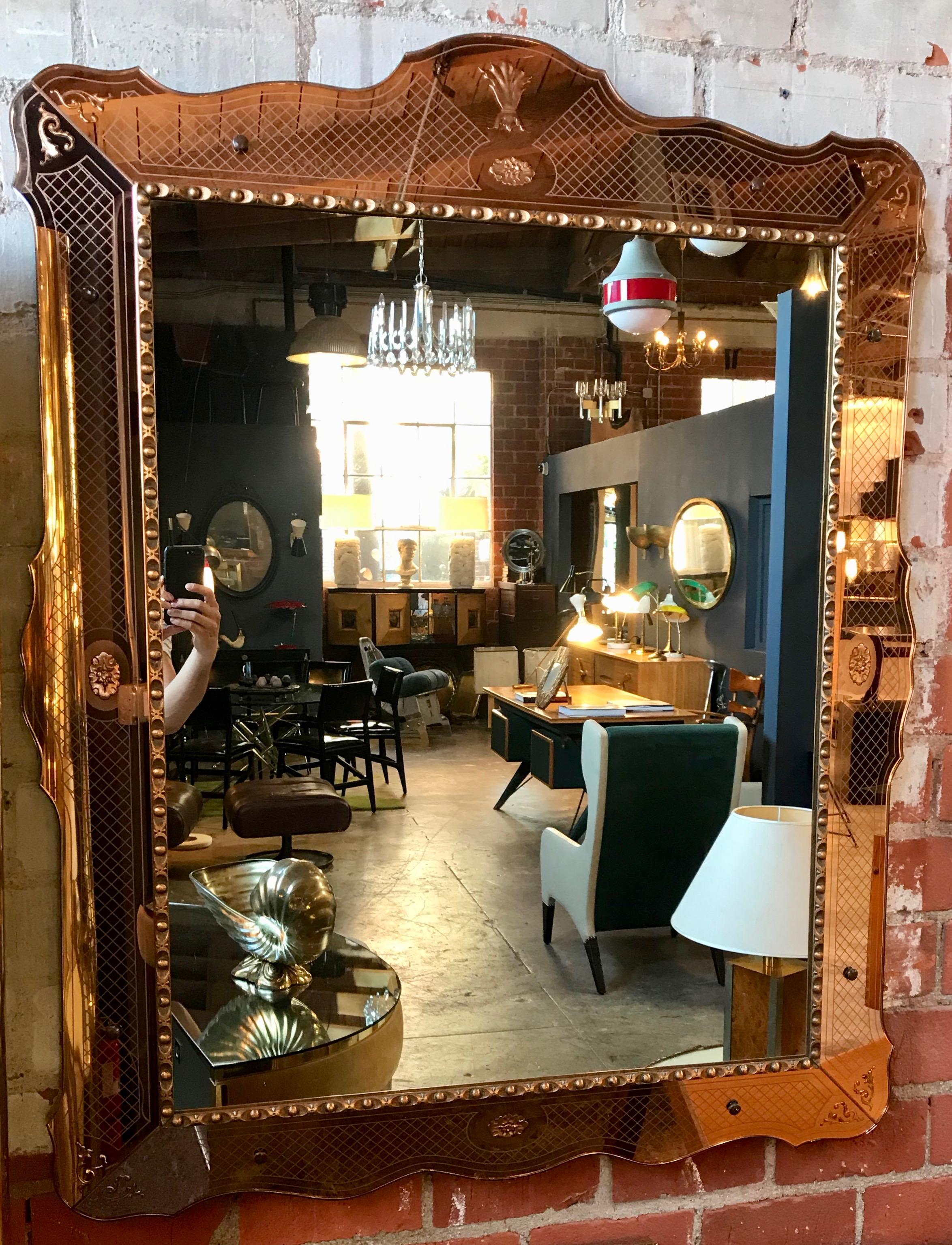 Glass framed wall mirror crafted in clean lines with a touch of classical whimsy. Copper toned frame with opposed etchings. A nice piece for unifying varying themes within a room. From Venice, Italy, circa 1960 vintage.