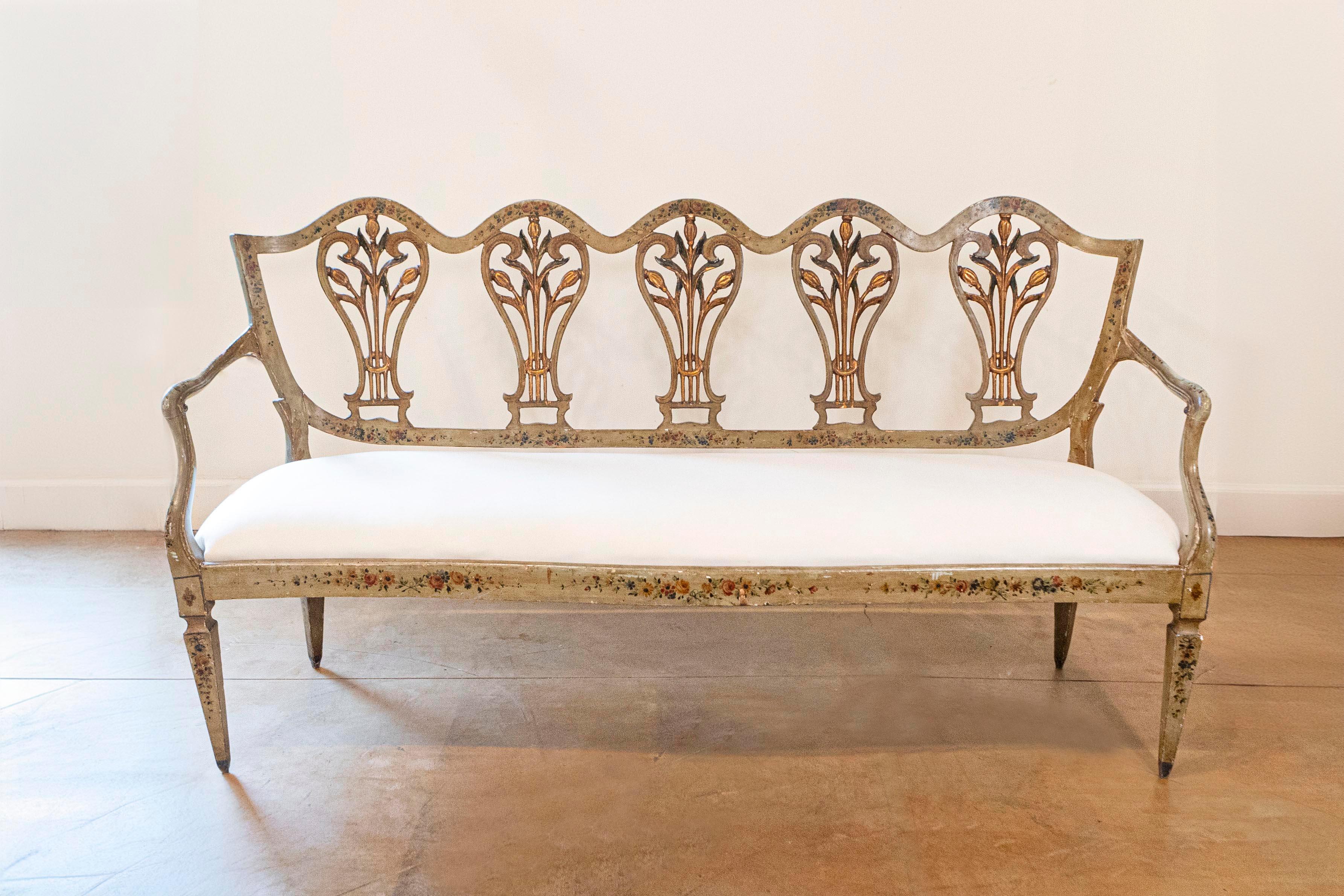 Canapé vénitien en bois peint et doré du XVIIIe siècle avec une nouvelle tapisserie. Ce rare canapé italien présente un dossier ajouré, surmonté d'un rail sinueux, orné de délicats motifs floraux peints. Ce dos est décoré de cinq cannelures percées,