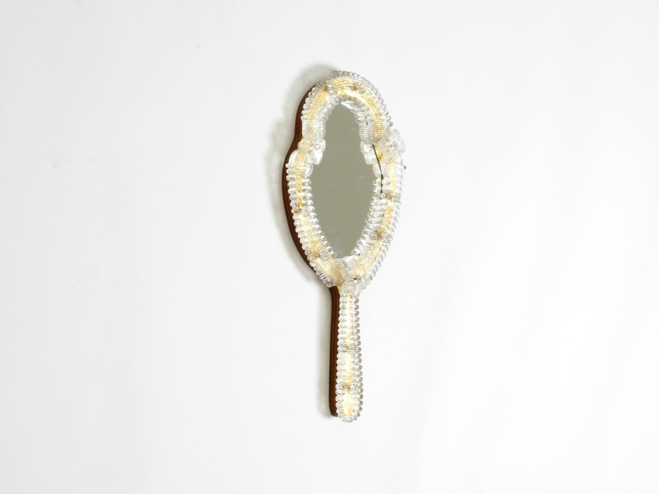 Beautiful Venetian Mid-Century Modern handheld or wall mirror with Murano glass rosettes. Made in Italy. The glass elements are shaped like blossoms.
A stunningly beautiful mirror with many details.
Very high-quality craftsmanship in very good