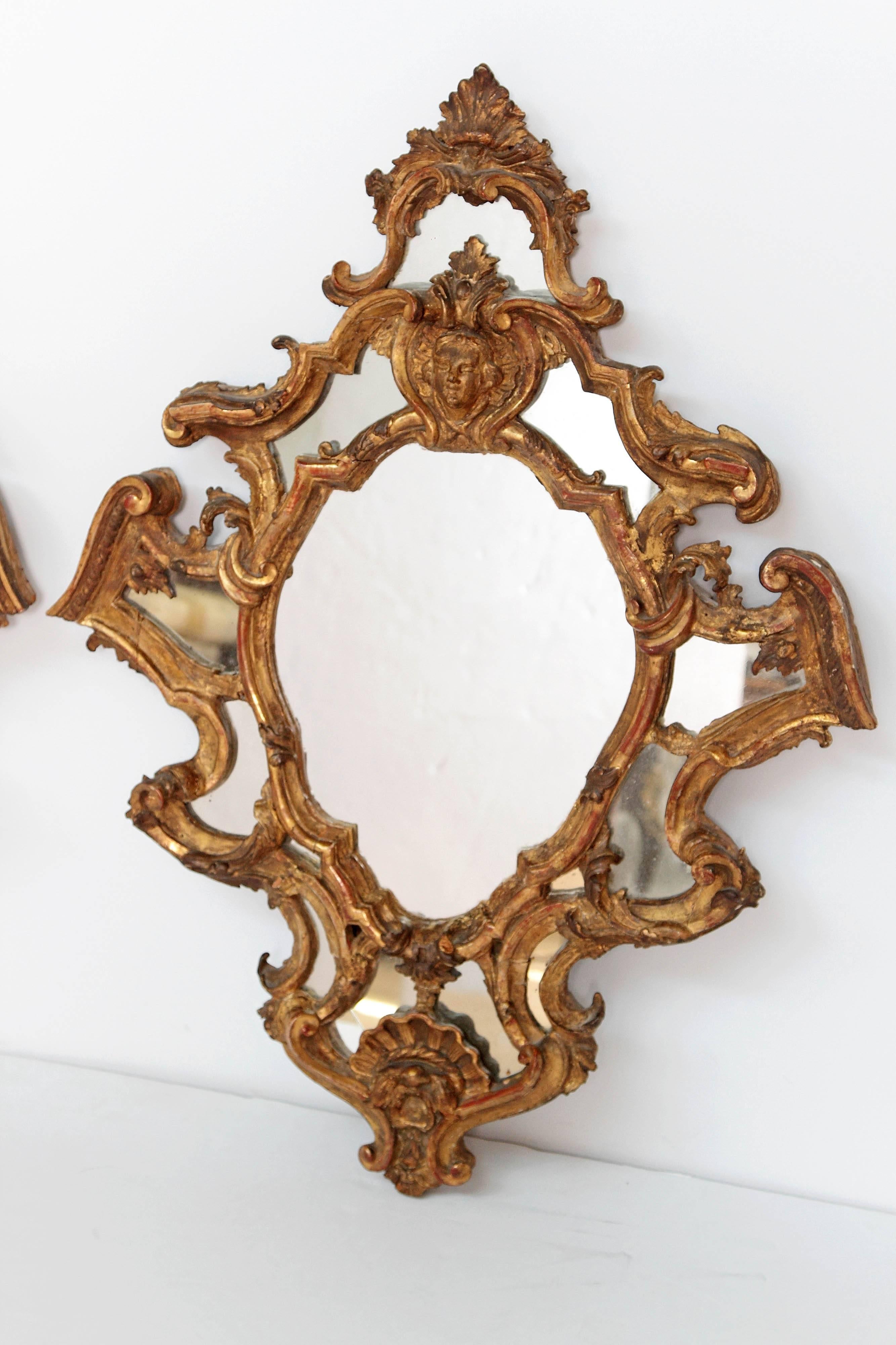 A beautiful pair of elaborately carved Venetian giltwood mirrors. Female masks mounted on the top with curves and internal reserves separating the mirror plate.