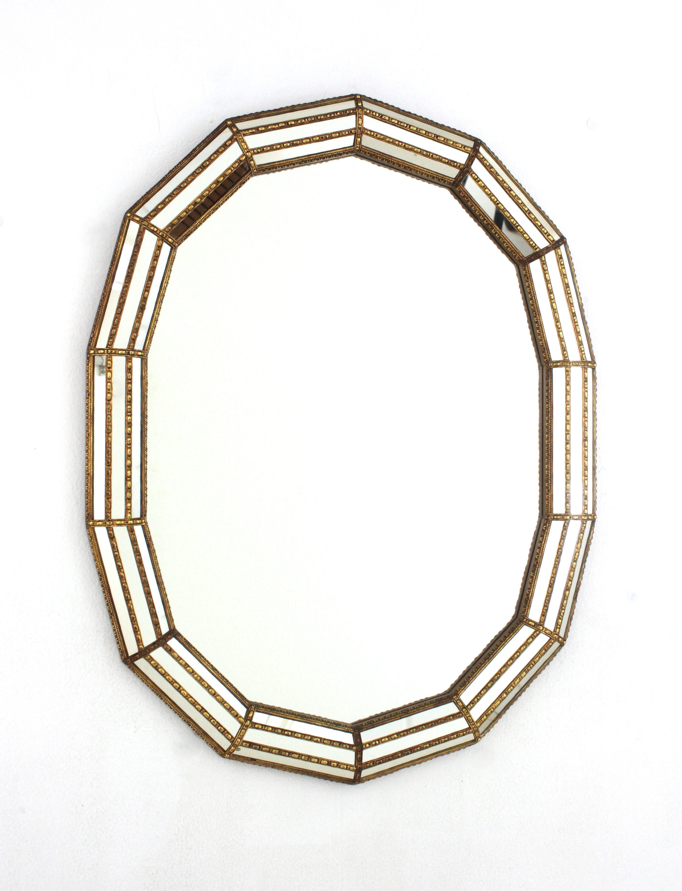 Venetian style Regency modern oval wall mirror with gilt metal accents, Spain, 1960s
Oval shaped mirror made of 14 sides. Triple mirror mosaic frame cased into a gilt wood structure. The mirrored panels are adorned by brass classical patterns.
This