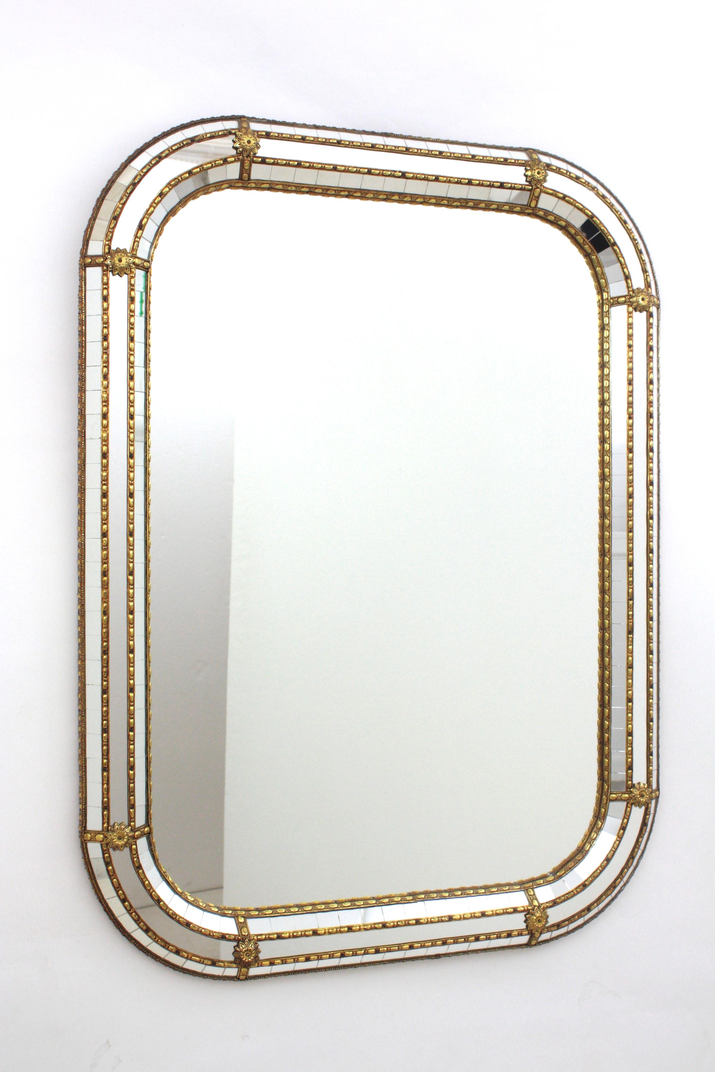 Venetian style rectangular wall mirror with round corners and gilt metal accents, Spain, 1960s
This wall mirror has a triple mirror frame with rectangular shape and rounded corners. The central layer is made of mirror glass and the other two layers