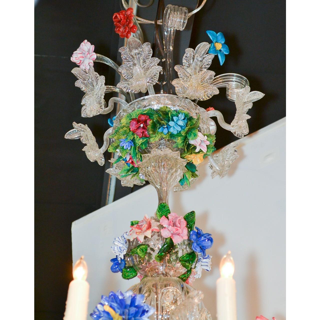 Prächtiger venezianischer Kronleuchter aus dem frühen 20. Jahrhundert aus mehrfarbigem Glas in Grün-, Blau-, Lavendel-, Rot- und Rosatönen. Die kunstvoll gestaltete Krone mit Blattrollen und Blattgirlanden ist mit Trieben bunter Wildblumen