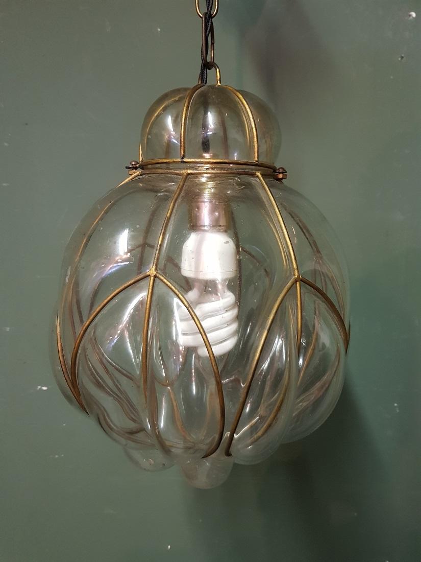 Beautiful model of an old Venetian Murano hanging lamp made of clear glass blown into a metal frame and surrounded by air bubbles in the glass. It is further in good condition with new wire and fitting. Originating from the mid-20th century.

The