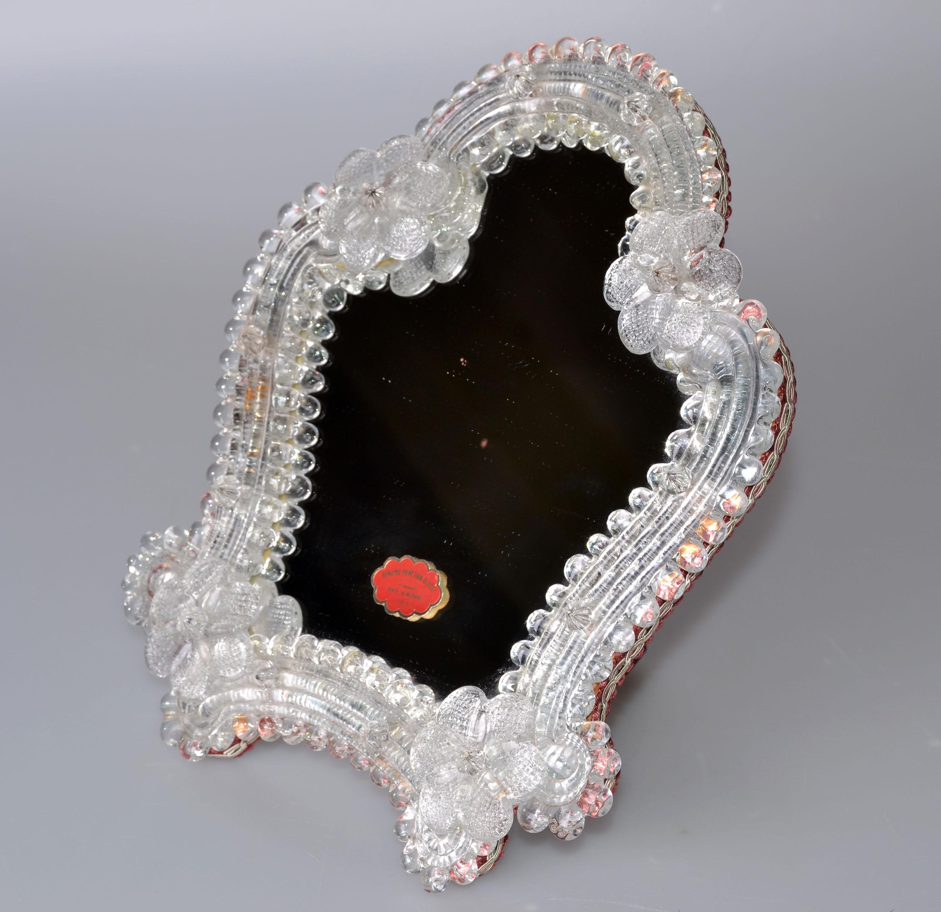 Lovely desktop Murano glass vanity mirror from Italy. 
Decorated with handmade Bohemian flowers and supported with a wooden back.
Original label on the mirror. 
Mirror size: 6 inches x 7 inches.