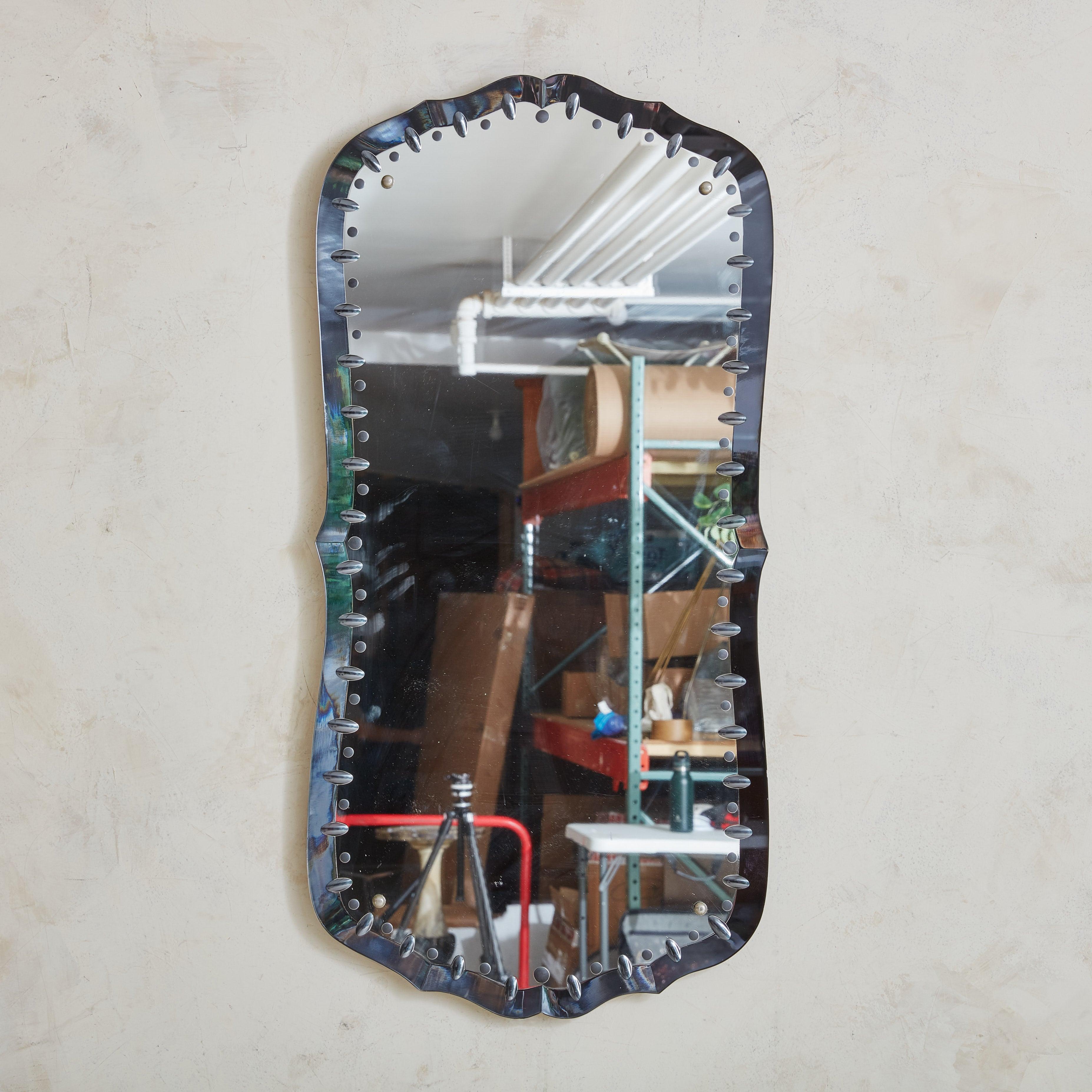 A Venetian style wall mirror featuring smoked Murano glass in a deep, gray hue. The wavy, etched border is accented with elegant geometric notch details. This piece would be a beautiful addition to an entryway or powder room. Bracket for hanging is