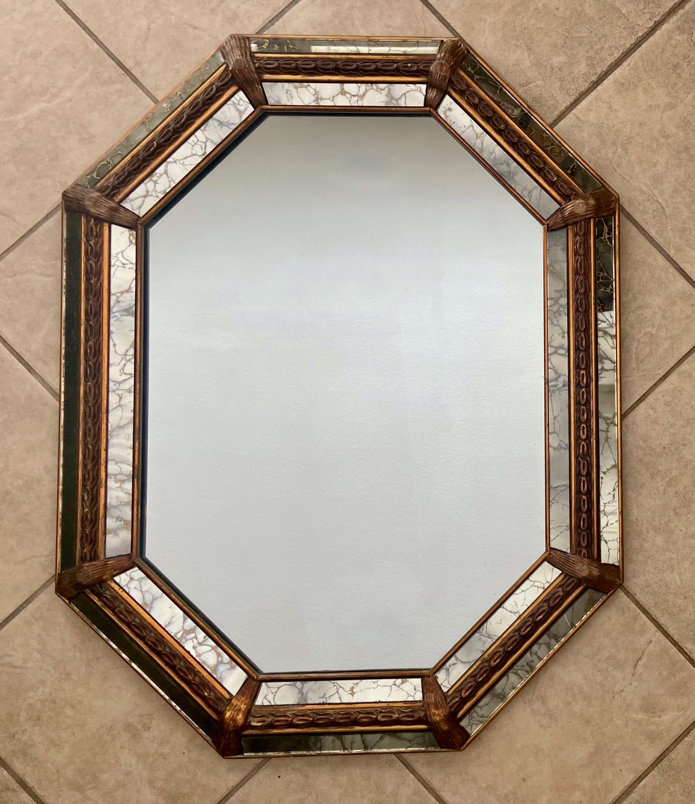 Venetian style 8 sided gilt wood wall mirror, accented with raised decorative carvings and gold vein mirror panels. A wonderfully crafted Hollywood Regency mid-century period wall mirror.
  