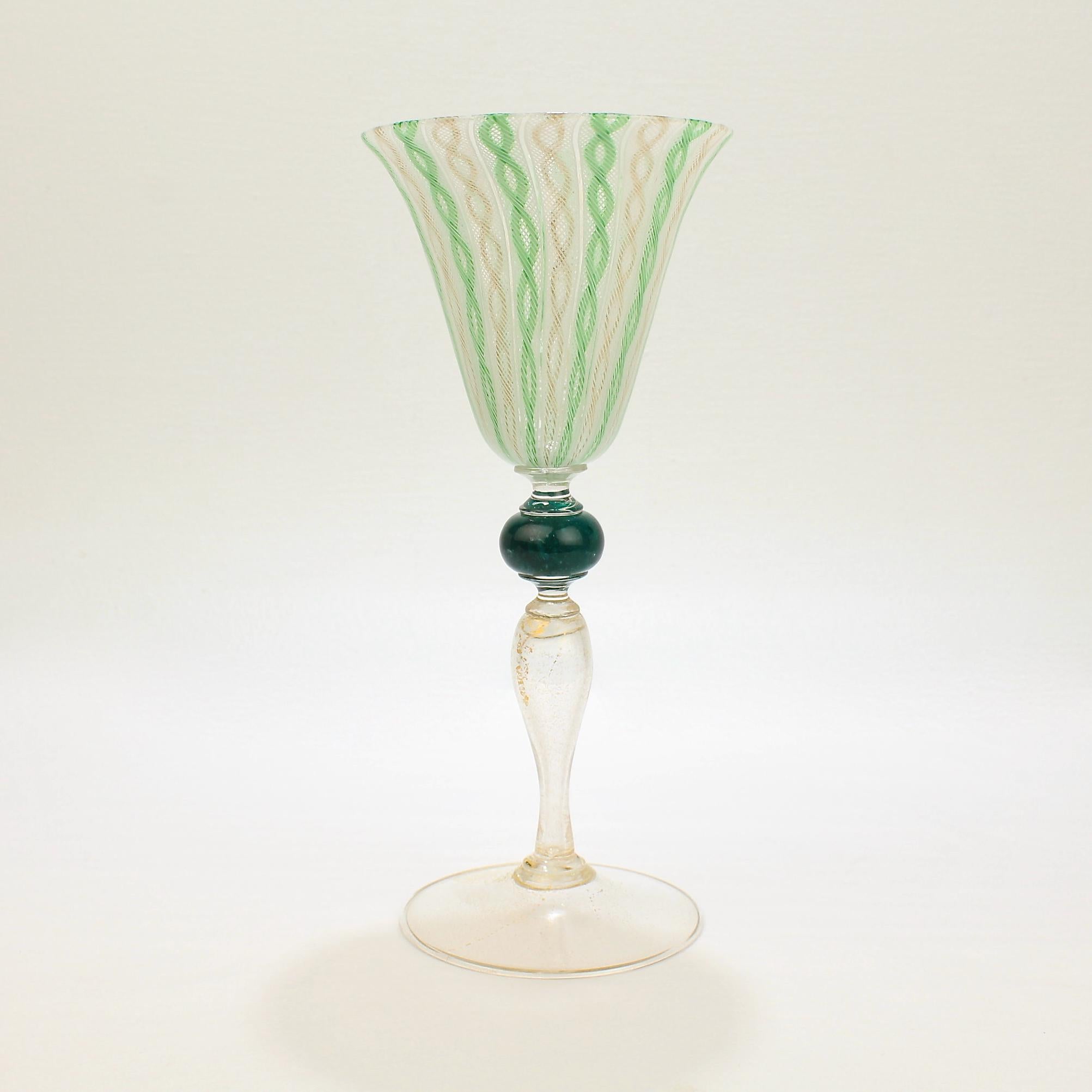 A wonderful large Venetian glass wine goblet with green, white, and gold latticinio swirl decoration. 

The goblet bowl rests on a suppressed ball knop, and the stem and foot have gold inclusions.

Attributed to Salviati.

Very fine