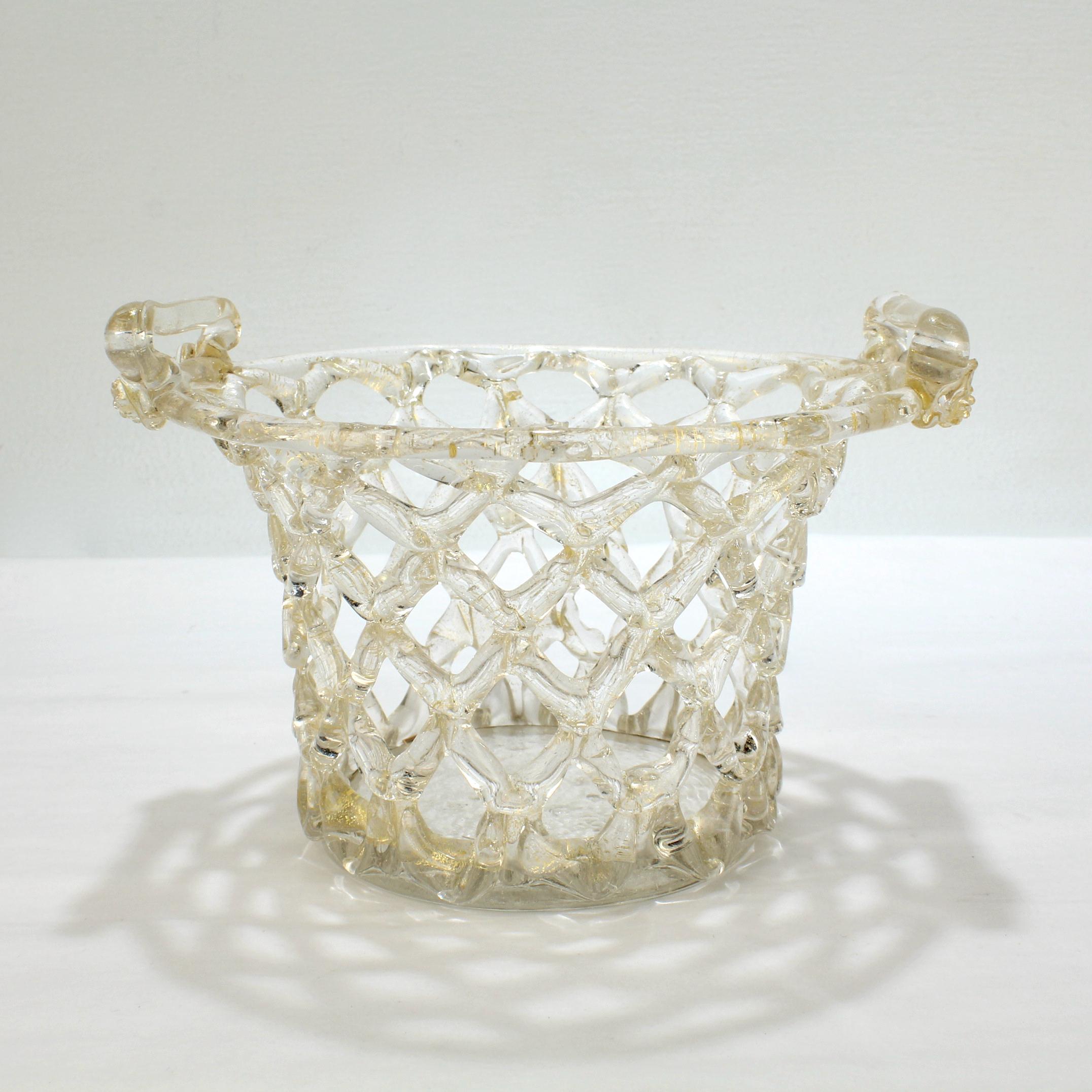 A very fine Venetian glass 'Liege a Traforato' bowl or basket.

In clear glass with gold foil inclusions, loop handles with applied button prunts, and a wafer foot. 

Simply an amazing openwork basket!

Provenance: 
From the estate of