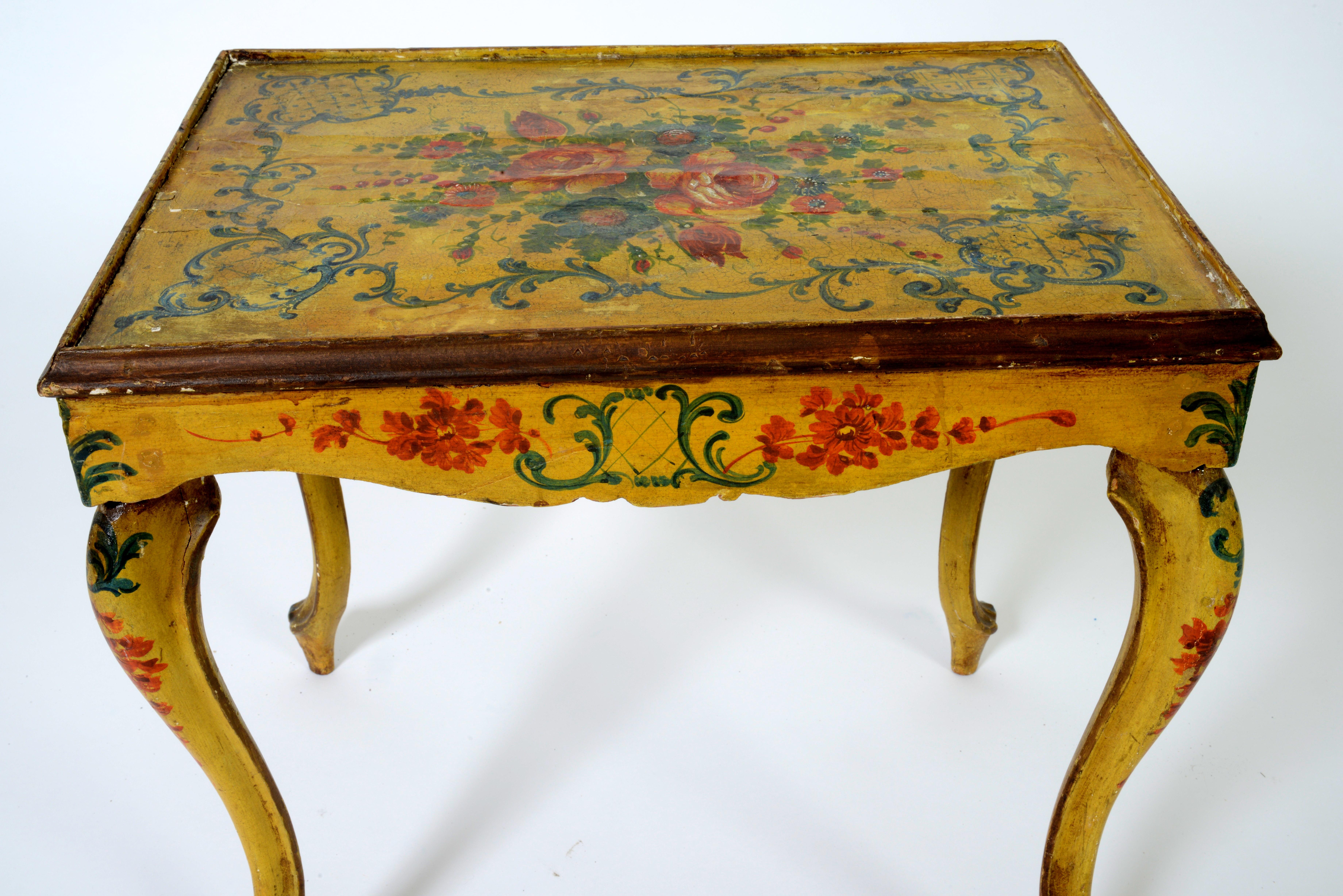 This beautiful hand-painted Venetian table has a yellow ground with green scrolls and red foliate decoration. It has a scalloped apron and stands on cabriole legs. The top has a painted canvas applied over the wood with a glass insert. The