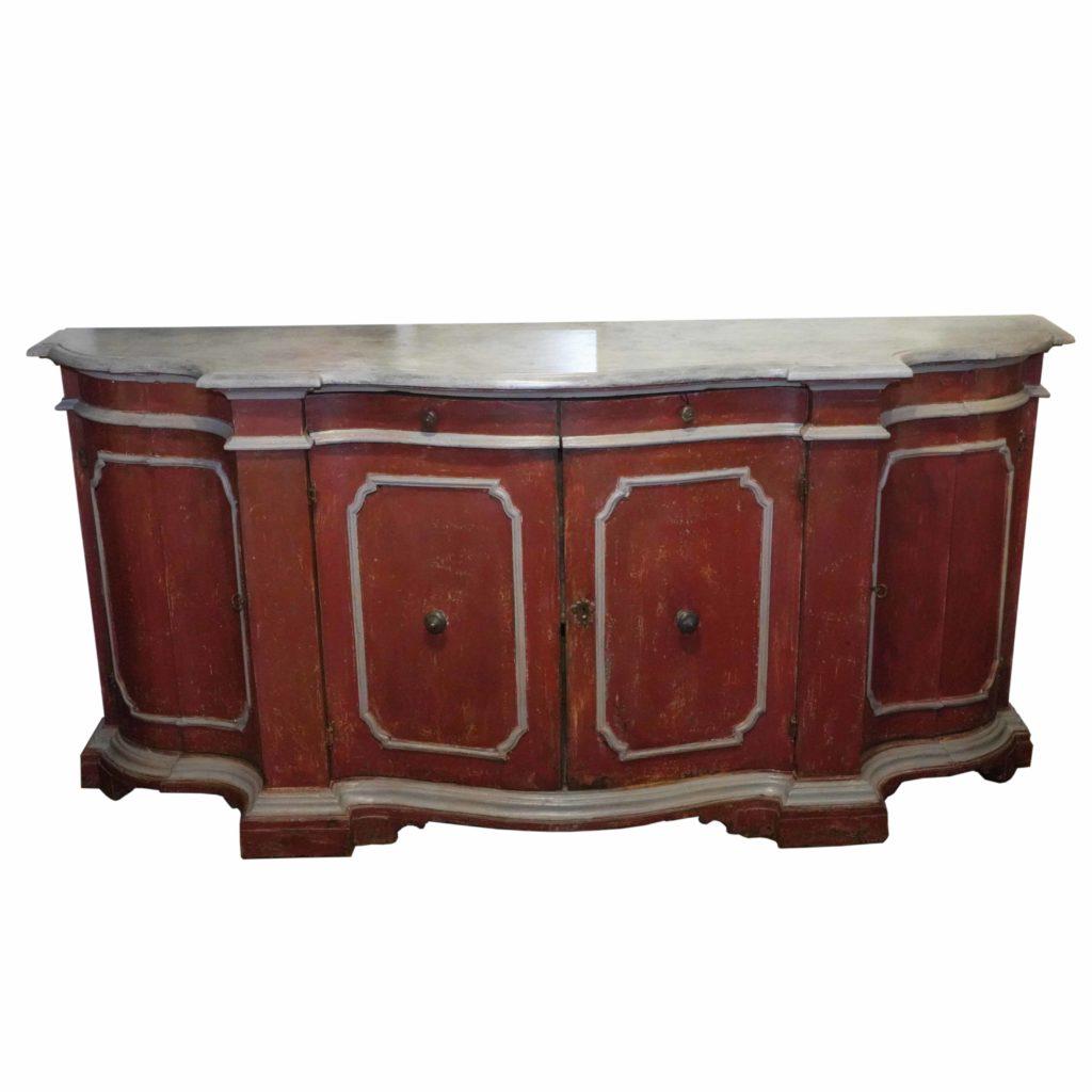 This Italian Venetian red painted credenza from the mid 19th century is a real show stopper! Featuring a contoured top, which follows the serpentine silhouette of the front, the piece is made with two thin drawers over four doors. The eye is