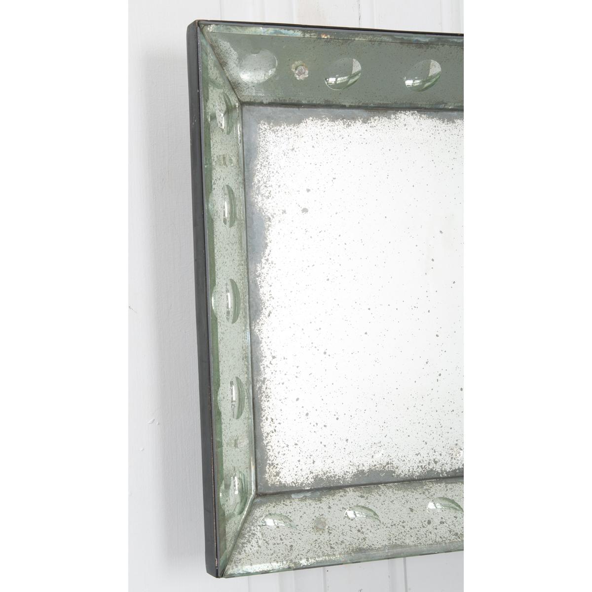This reproduction mirror imitates the look of a vintage mirror with a few extra details. Twenty bullseye bubbles surround the main mirror plate with small glass flowers in between. Perfectly square, adding this mirror to your existing decor will be