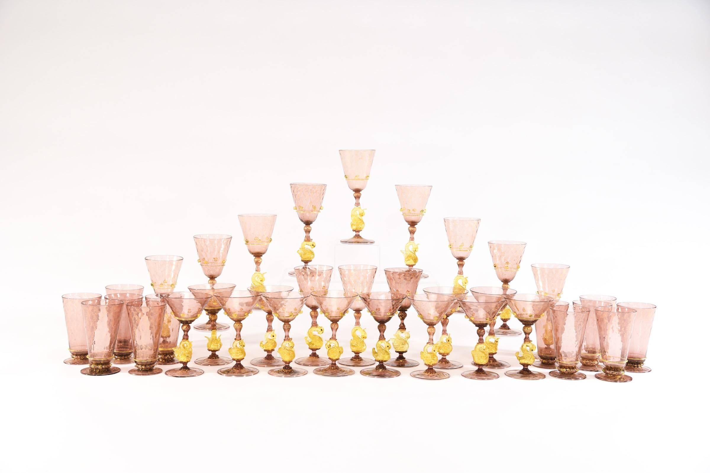 This is a complete hand blown Venetian stemware service made by Salviati, circa 1920s. The 36 piece set consists of 12 each of water goblets, wine goblets and champagne coupes, each one featuring a figural golden yellow swan connector and applied