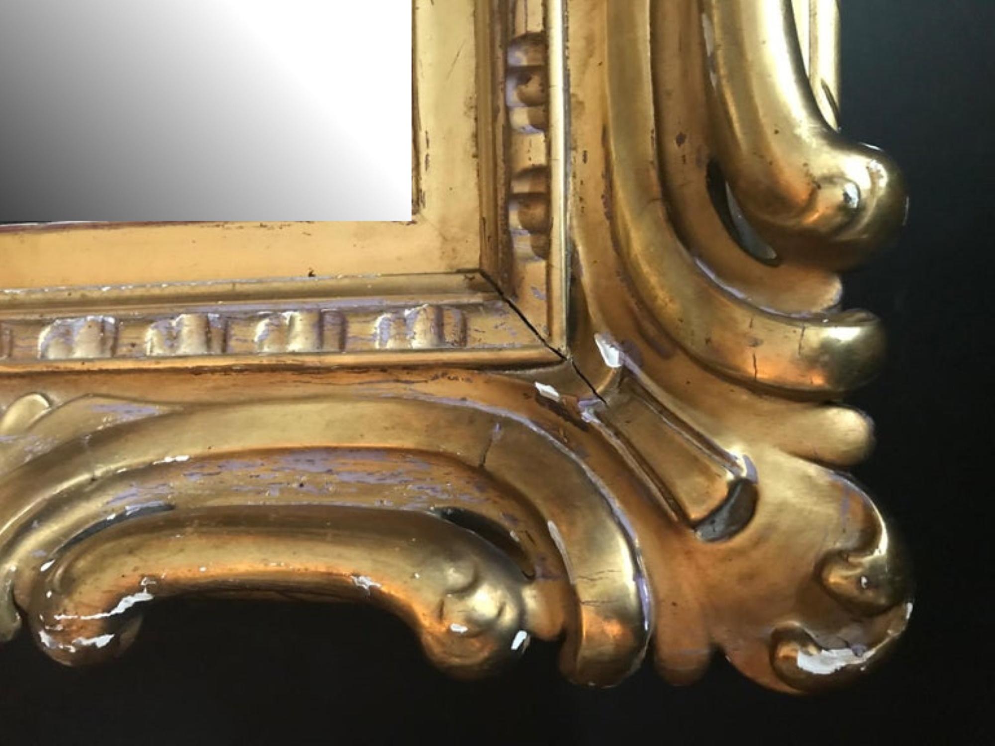 This is a magnificent antique Venetian Sansovino style high relief carved, richly water gilded and highly burnished framed mirror. It is certainly an outstanding 19th century large scaled museum quality piece. The opulent and bold carving makes a