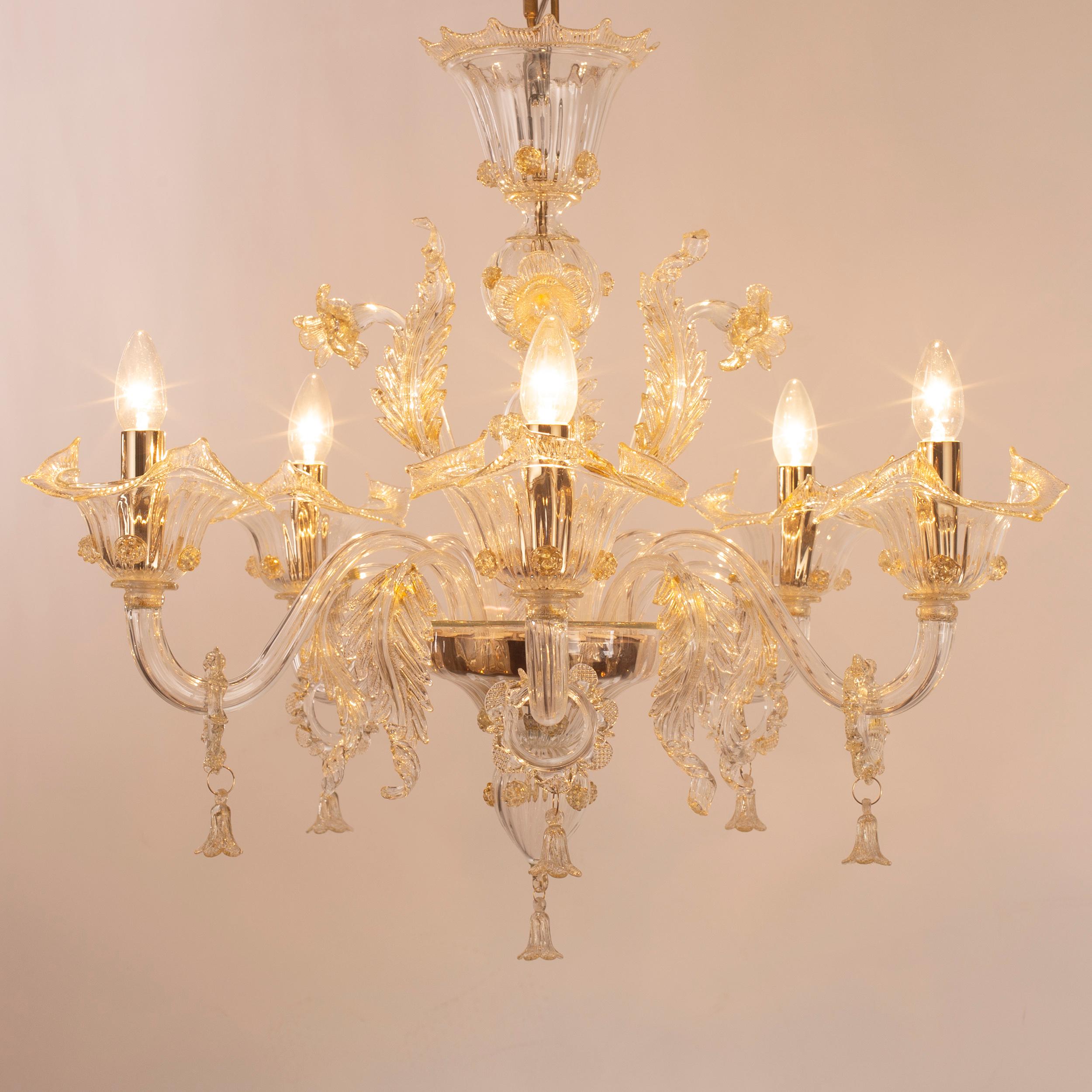Bovary chandelier, 5 lights, in clear artistic glass, with golden details by Multiforme is a luxury chandelier that will never be outmoded.
This collection takes inspiration from the Classic floral Venetian chandeliers, and it is available in many