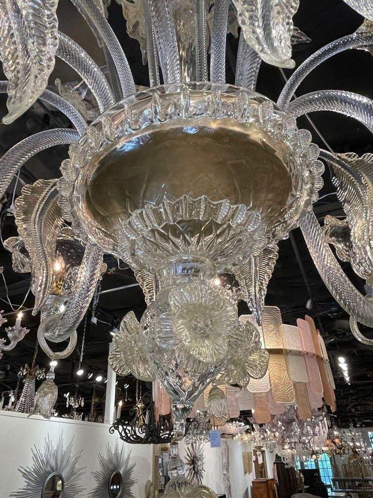 Questo lampadario in vetro di Murano in stile veneziano presenta intricati disegni di foglie e fiori che aggiungono un tocco di eleganza e raffinatezza a qualsiasi spazio. La delicata lavorazione artigianale e l'attenzione ai dettagli del vetro