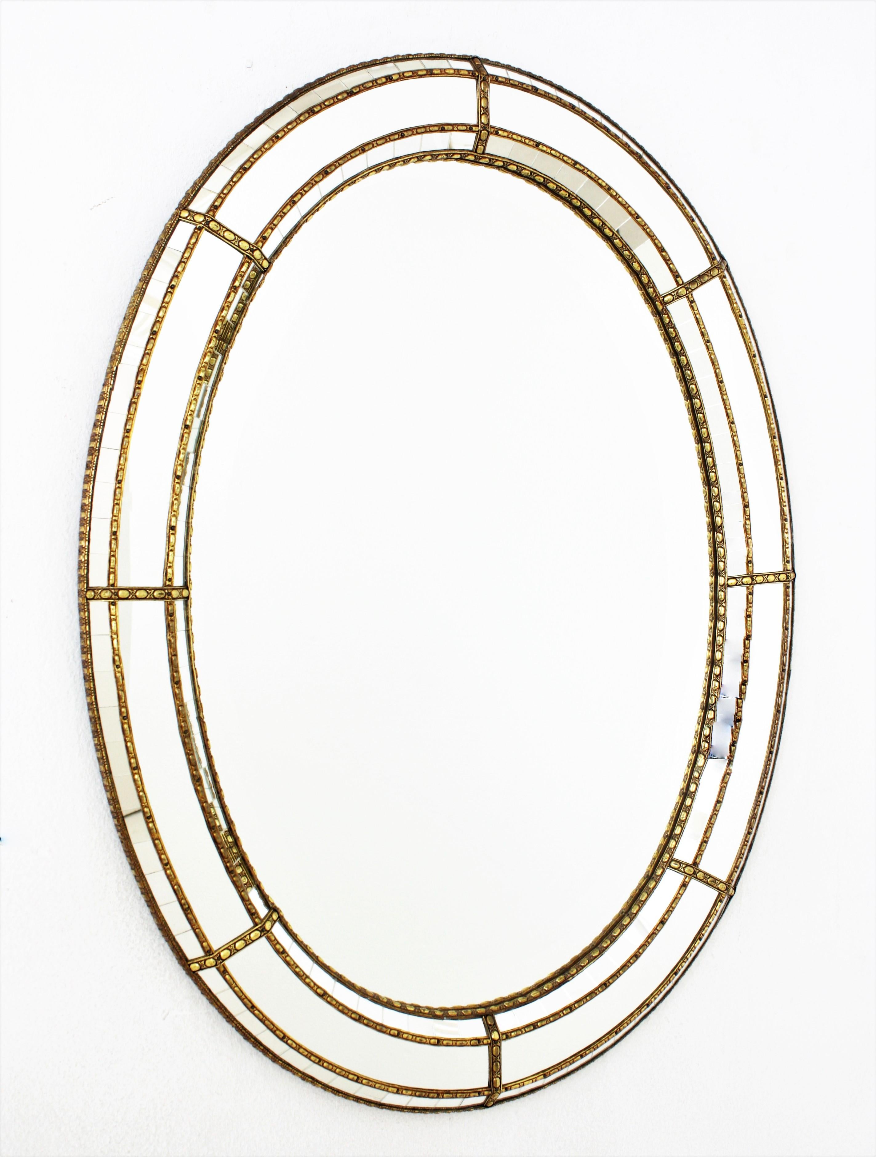 Elegant Venetian style Hollywood Regency oval mirror with brass details. Spain, 1960s
This glamorous mirror features a triple layered mirror frame made of brass. Oval form with a frame that has three layers of decorative paneled mirrors. The biger