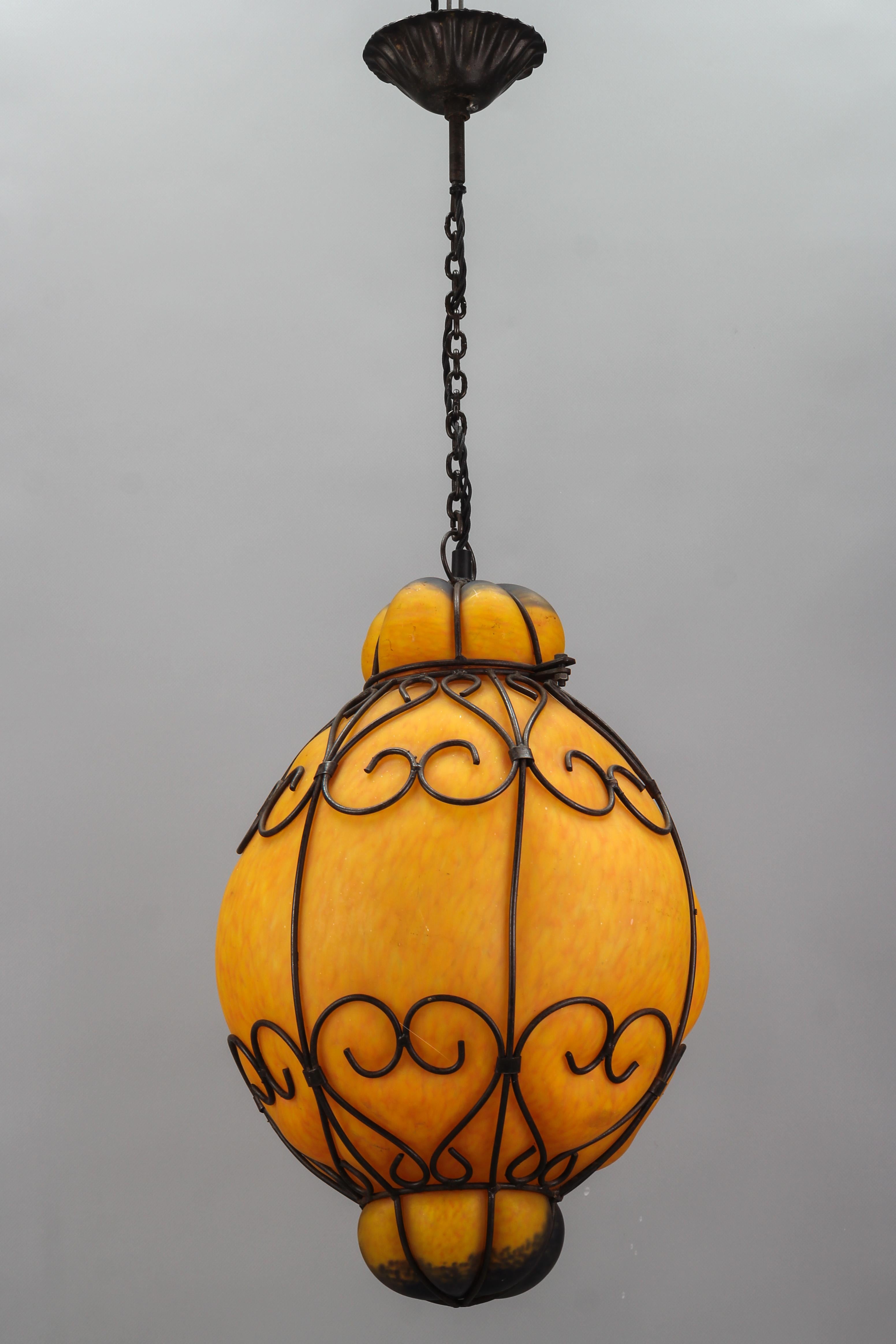 Venetian Style Pâte de Verre glass metal caged lantern pendant light, France, 1970s.
Impressive and large hand-blown Pâte de Verre glass lantern in orange and dark blue tones formed within a decorative metal cage. The different shapes of the glass