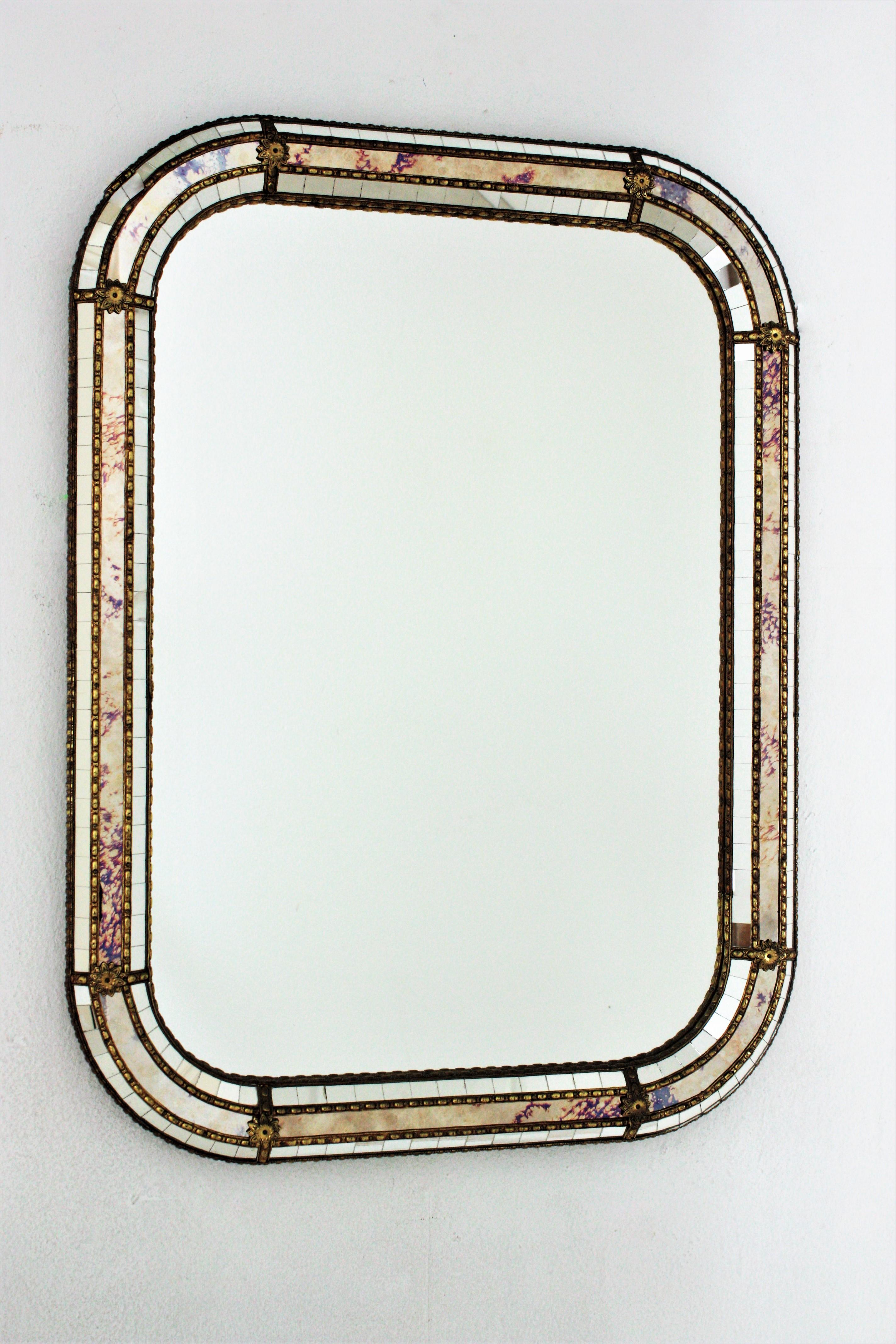 Venetian style rectangular wall mirror with iridiscent glasses and gilt metal accents, Spain, 1960s
This wall mirror has a triple mirror frame with rectangular shape and rounded corners. The central layer is made of iridiscent glasses in shades from