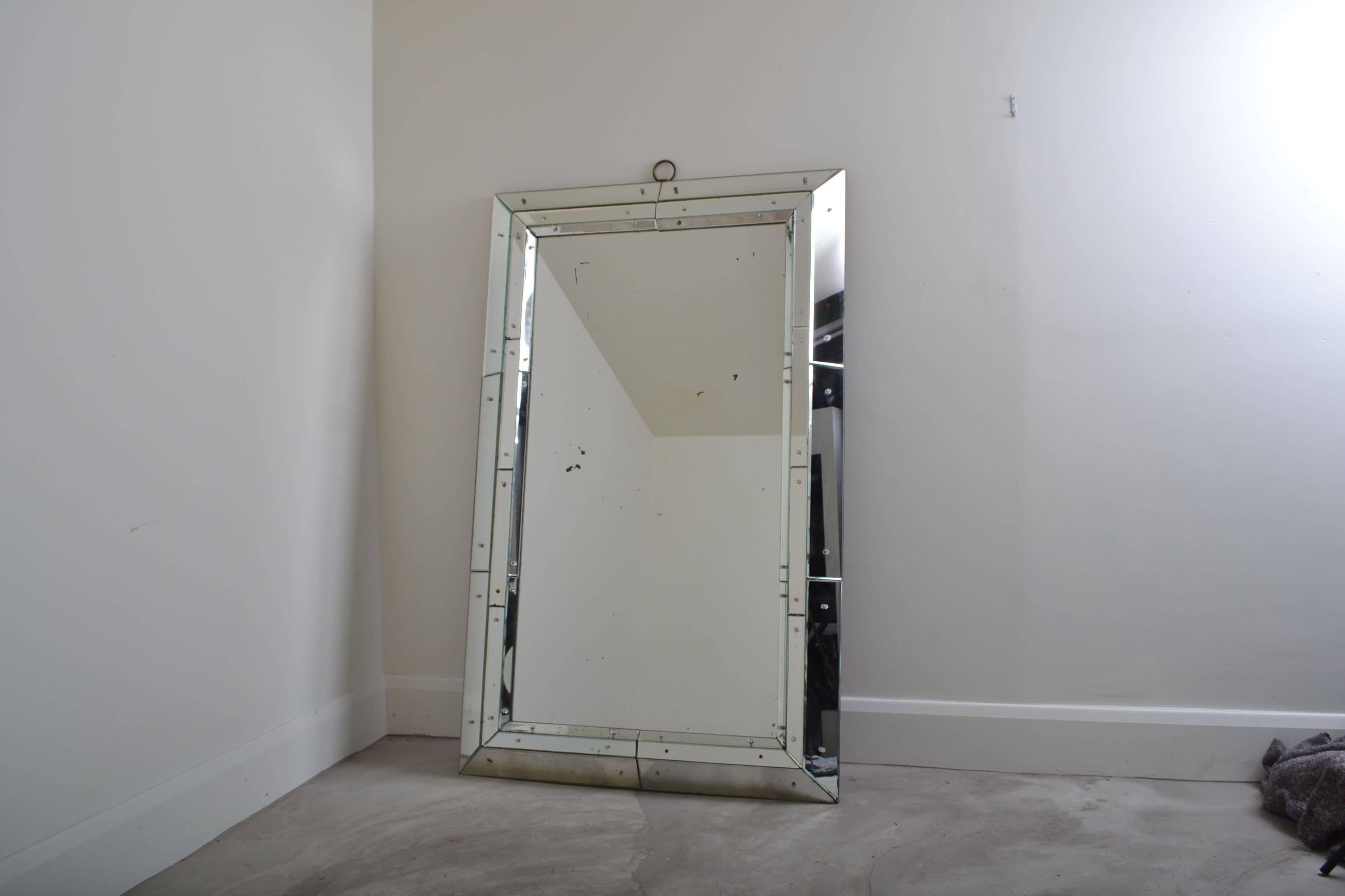 Very unusual sectional glass Venetian mirror in the style of Jacques Adnet.
The mirror is of impressive scale and has an circular iron decorative motif at the
top which can be found on other Jacques Adnet designs.
There are some black oxidisation