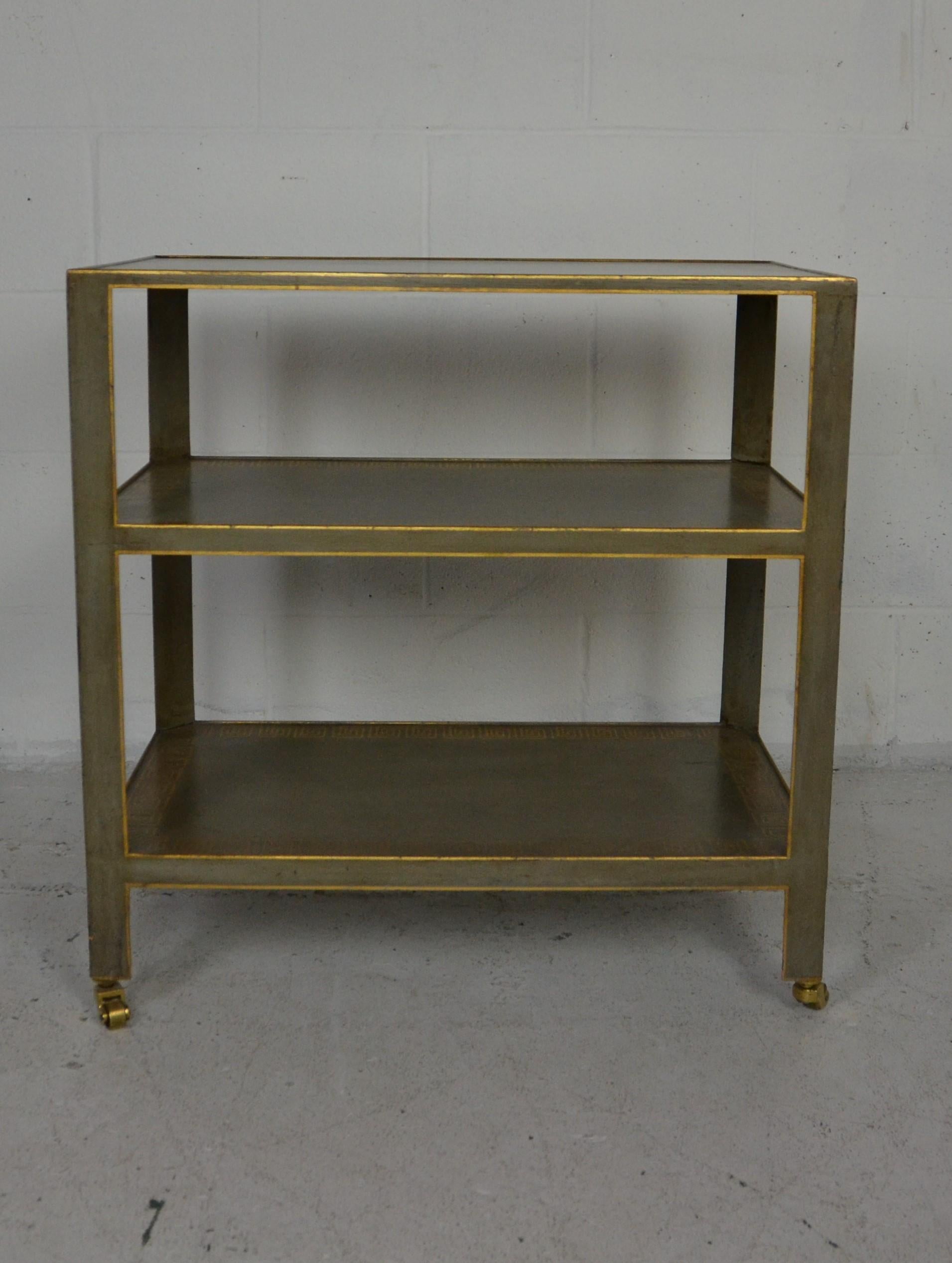A 3 tier Venetian style tea cart. Original gray/teal paint finish decorated with a hand painted design in the classical Greek style. Gold pin-striping to the edges. Solid brass castors.