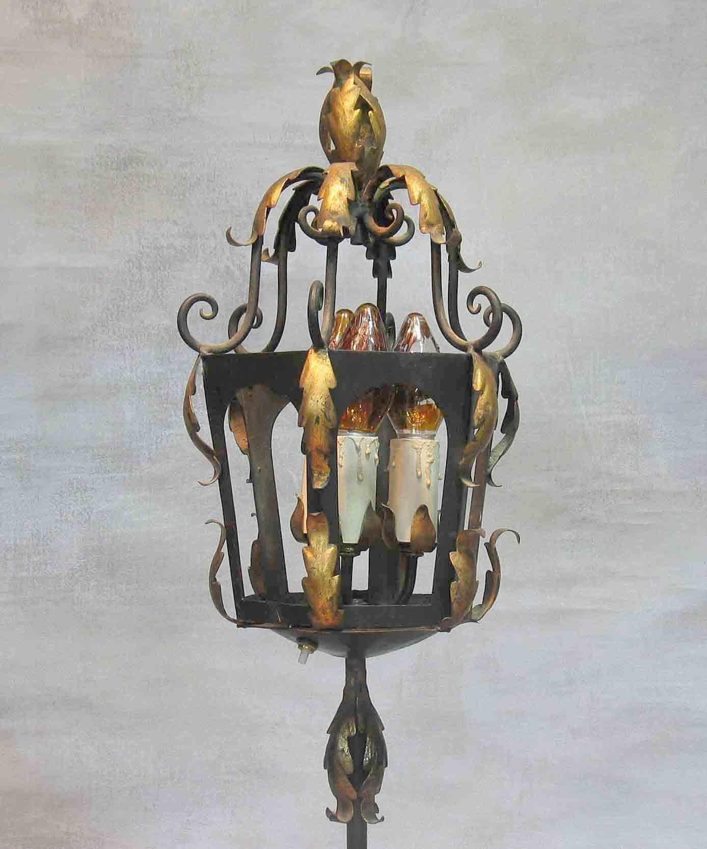 A Venetian style tole and wrought iron lantern floor lamp,
circa 1930.

Gilt and black painted tole and wrought iron
lantern. Shaft set into a turned gilt wood baluster
raised on a iron tripod base.

Measures: 60