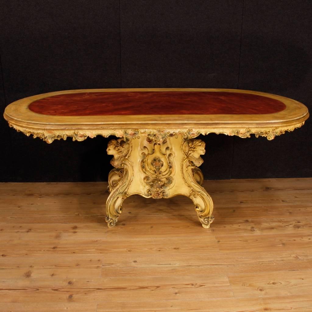 Great Venetian table from 20th century. Scenographic furniture richly carved with floral motifs and faces of little angels. Dining table in gilded and lacquered wood, of great decoration. It presents some drops of color, overall in good state of