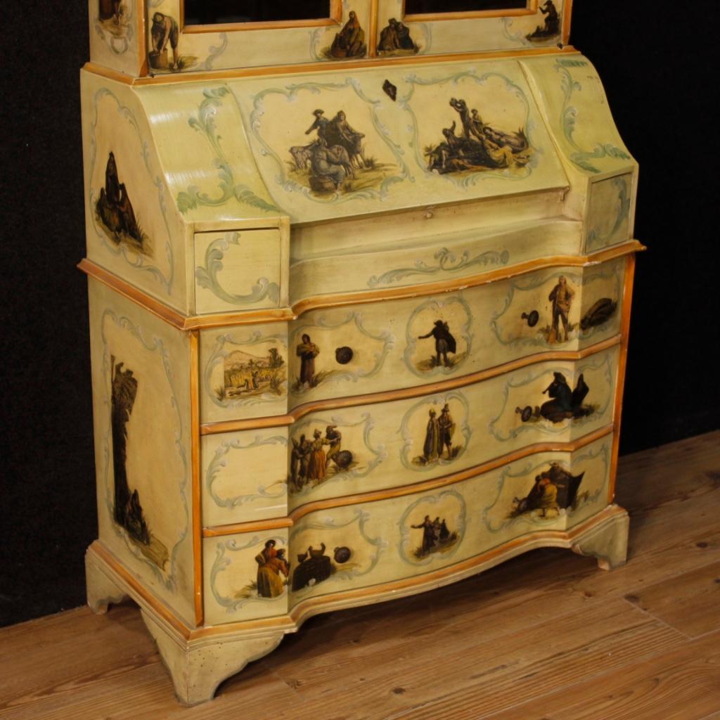 Venetian trumeau from 20th century. Double body furniture in carved, lacquered, painted wood adorned with applied prints depicting characters in Venetian style. Lower body complete with three external drawers of good capacity and a fall-front desk