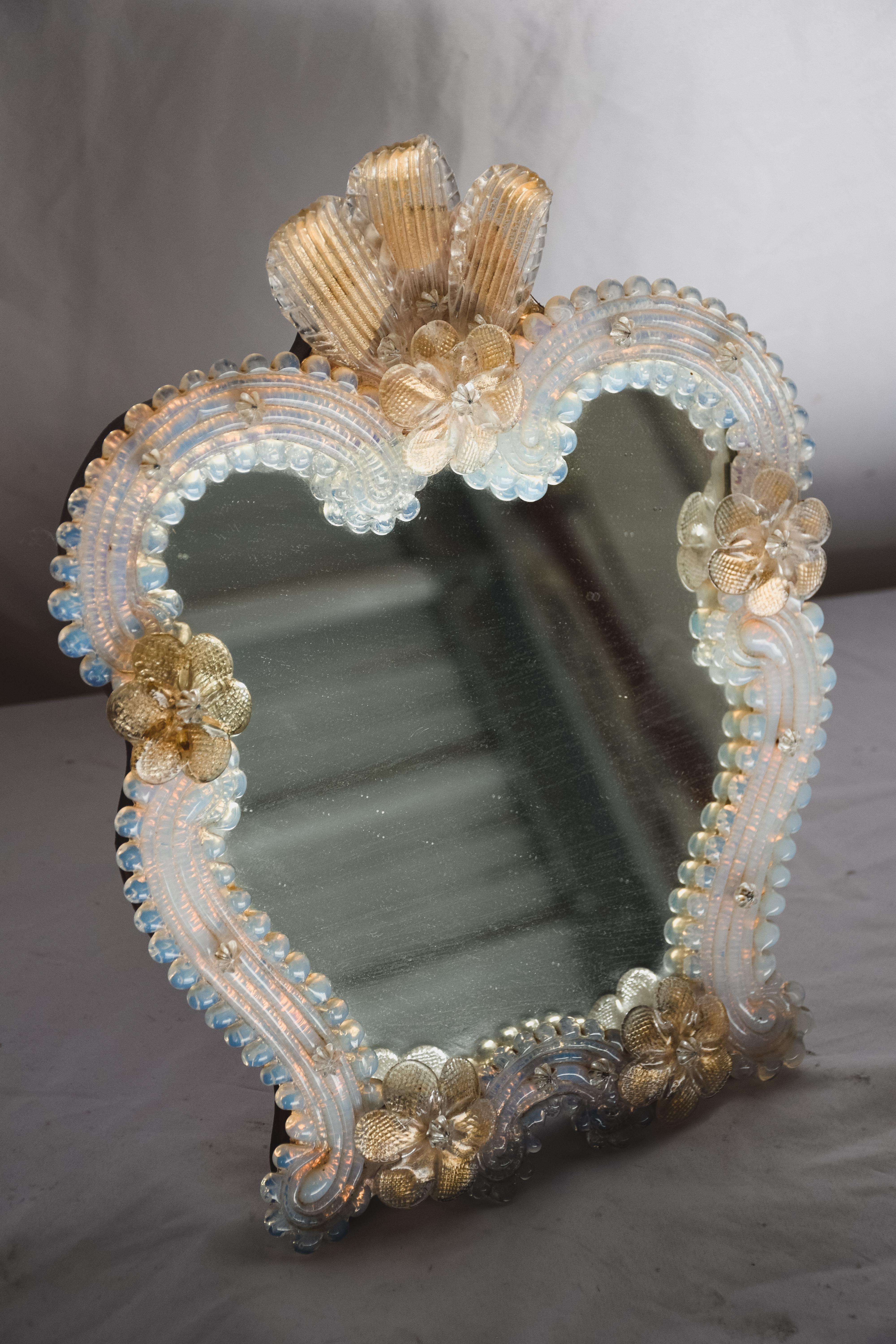 Miroir vénitien du milieu du XXe siècle avec des accents floraux. Fantastique miroir de table vénitien vintage sur pied. Magnifique verre soufflé à la main avec des volants et des fleurs. Dos en bois avec support. 