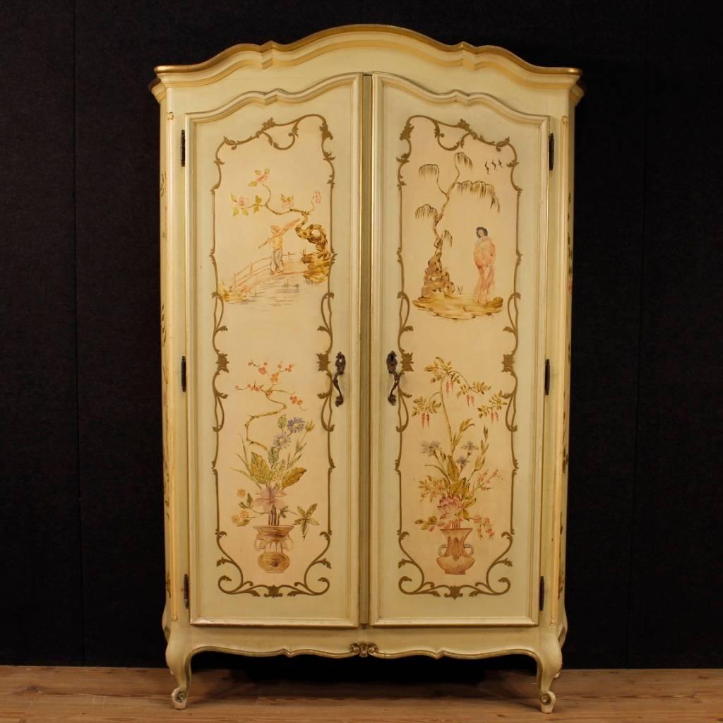 Venetian wardrobe from 20th century in carved, gilded and painted wood with floral decorations and chinoiserie scenes. Entrance furniture with two doors with internal parcel shelf and good-fitting clothes hanger. Wardrobe of particular proportions,