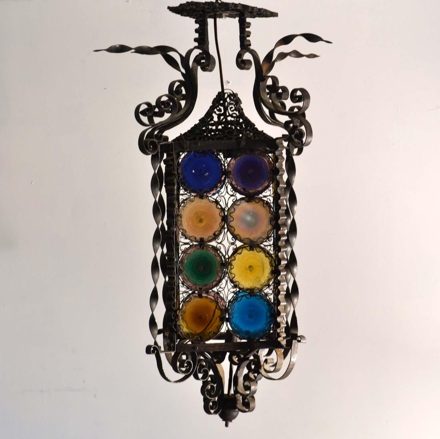 A late 20th century Italian wrought iron lantern with its multicolored stained round glass. Each disk is unique, hand blown and hand colored probably originated from the Venetian island of Murano with its beginnings since the 13th century. The