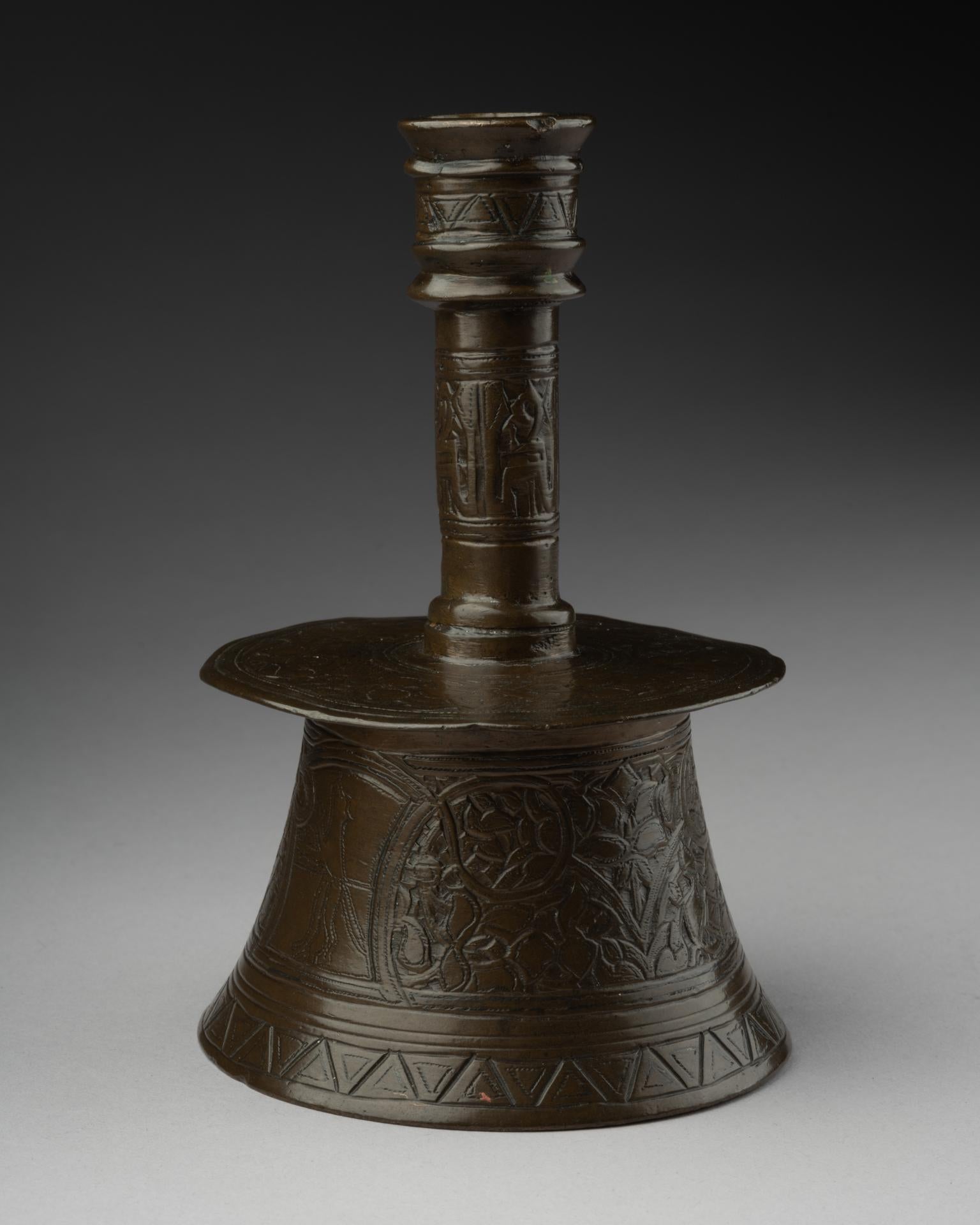 Chandelier vénéto-sarrasin
Bronze gravé
15e siècle
13 x 8,5 cm

Ce chandelier rare témoigne d'un savoir-faire exquis, avec une base en forme de cloche et un pied évasé orné de motifs gravés complexes. La décoration consiste en des motifs