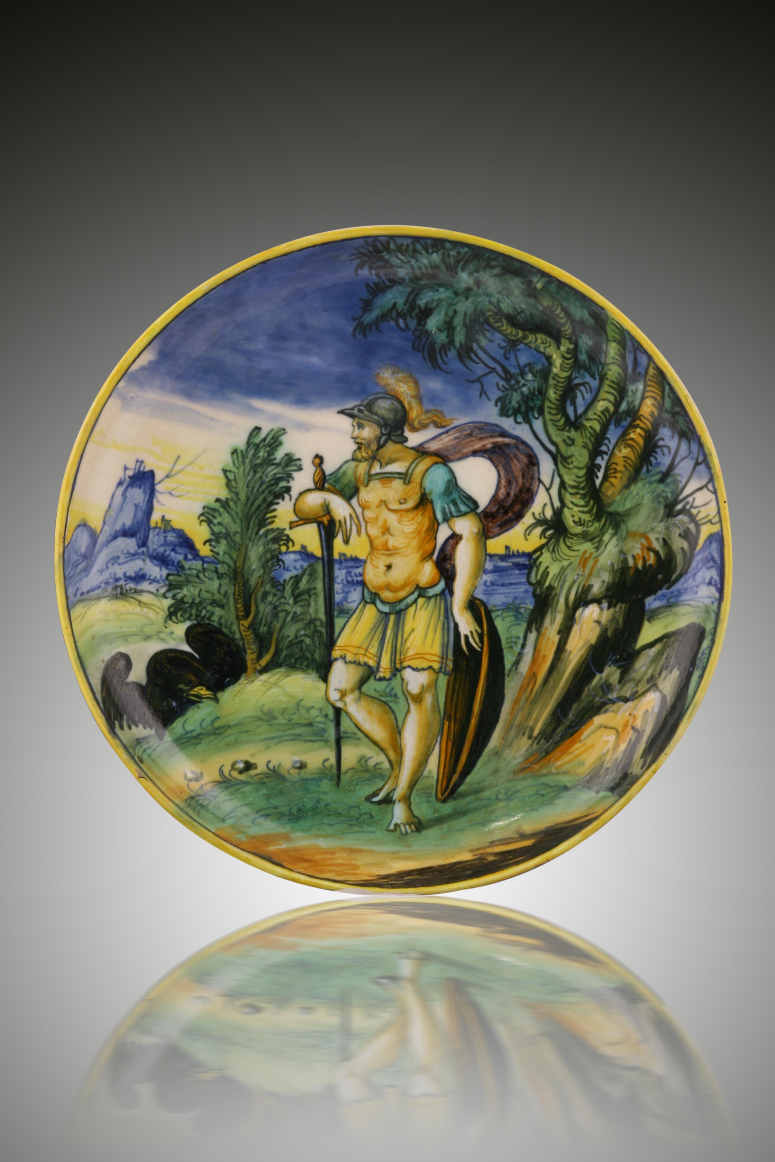A Venezia Maiolica istoriato footed dish, circa 1550-1560.
Probably by Mazo, painted with a scene depicting a soldier, perhaps Jupiter, watched by an eagle, all in a wooded landscape with sea and mountains.
Measures: Diameter 26.2 cm, height 4.7