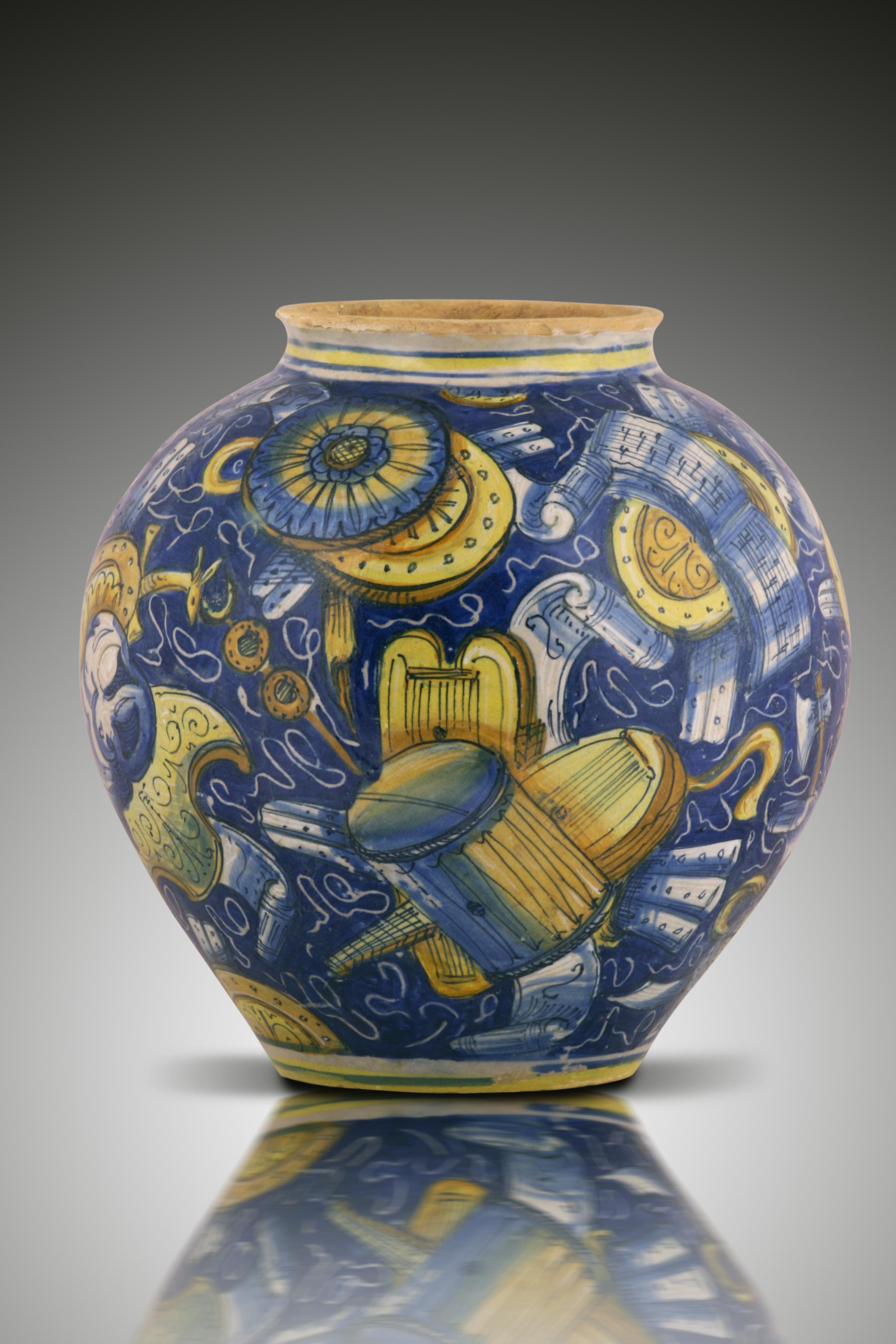 A Venezia vase-bowl Maiolica fully decorated in ochre, yellow, black on blue-ground scattered with military trophies including shields helmets, drums and music partitions. Concentric blue and ochre lines at the neck and foot. Workshop of maestro