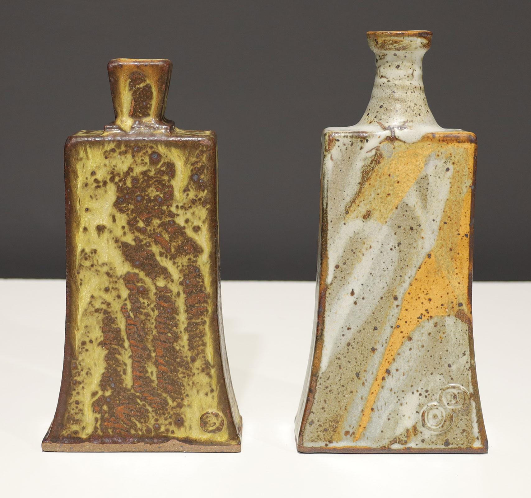 A beautifully executed pair of organic modern vases which are both stamped with makers mark. Browns, grays, whites and saffron colors illuminate these vases.  The larger is 10.5
