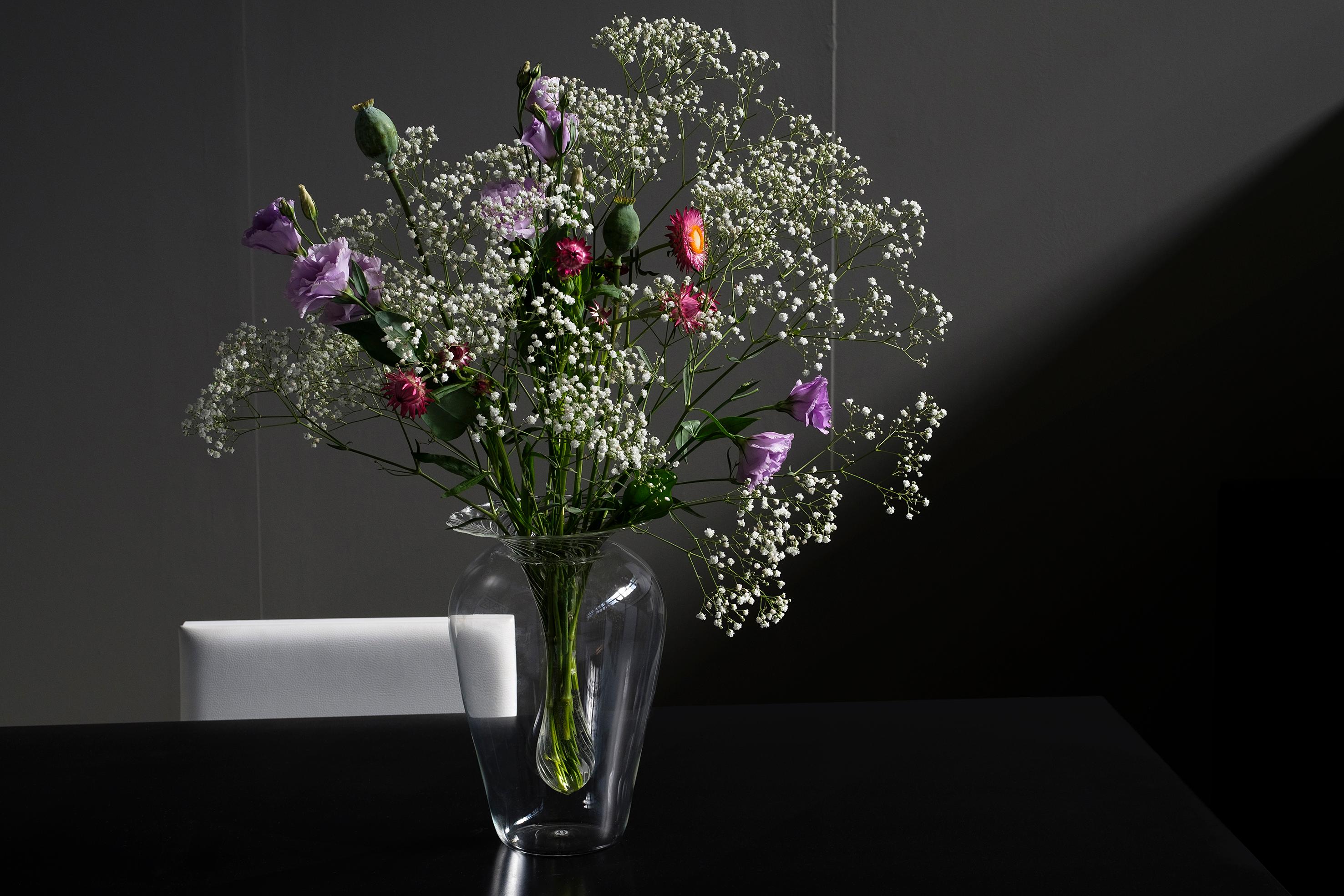 Vaso in due pezzi che esalta la versatilità del vetro borosilicato. Nella parte inferiore in vetro liscio, soffiato in una forma semplice e abbondante, poggia un inserto a righe a forma di goccia per ospitare un bouquet. Il vaso Twist è soffiato