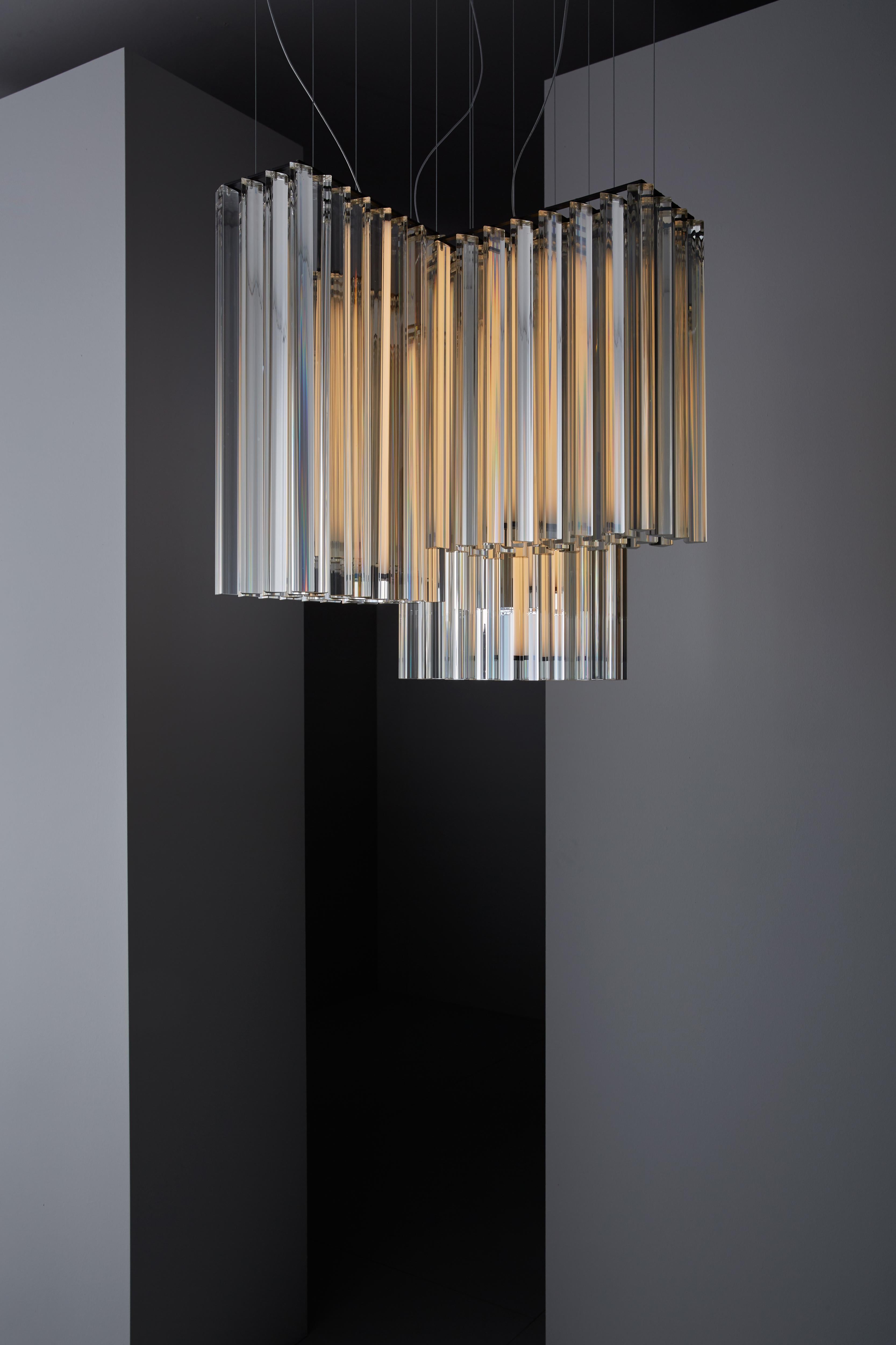 Suspended lamp with diffused light. Black metal structure with steel cables, composed of crystal triangular trihedrons. Strip LED inside the central cylindrical body.
 
Location: Interior
Light Source: 1×12W LED 1590lm 2700°K CRI90 + 2×17W LED