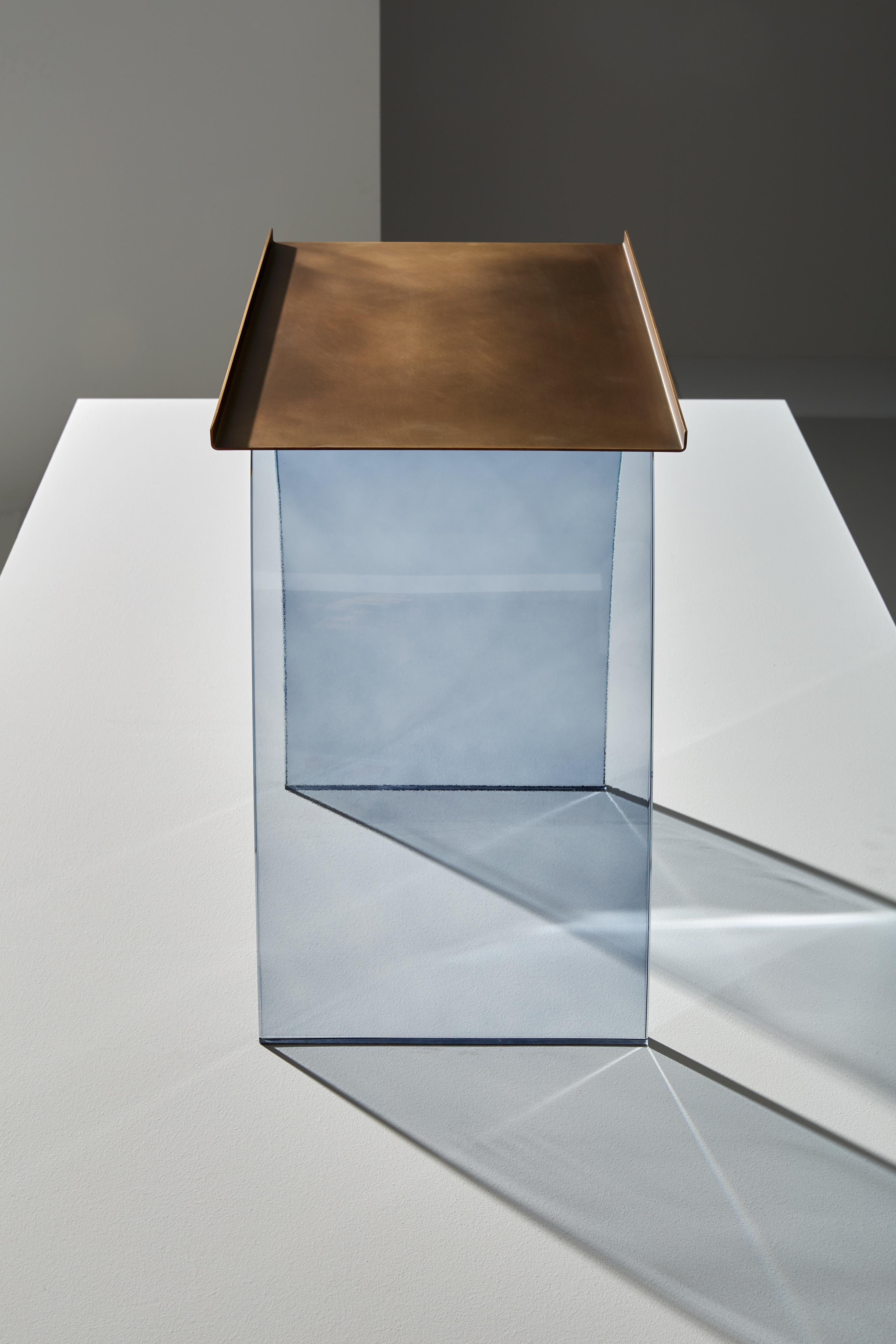 Table basse composée d'une structure portante en verre fumé courbé. Dessus en laiton légèrement bruni.
     