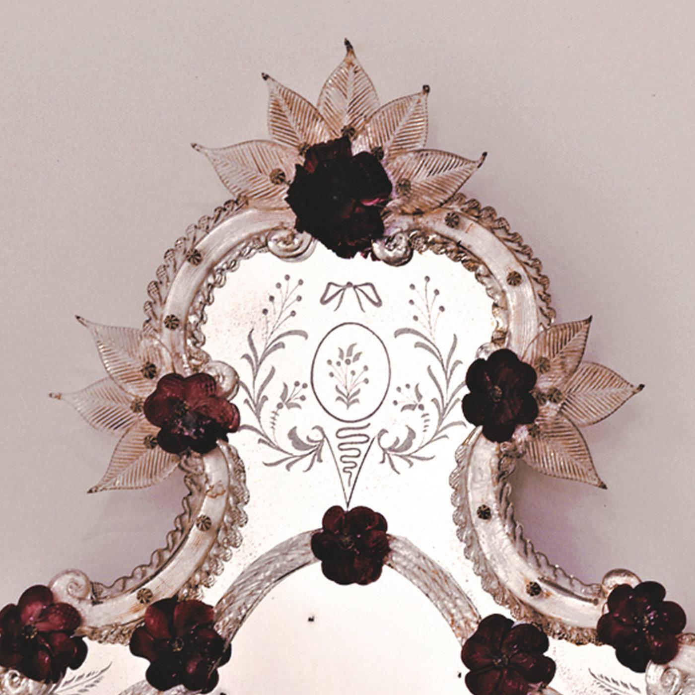 Cette charmante reproduction d'un miroir ancien présente un profil sinueux avec des insertions tridimensionnelles de roses et de fleurs en pâte de verre précieuse, de couleur corail, qui lui confèrent un charme délicat et féminin. Les détails