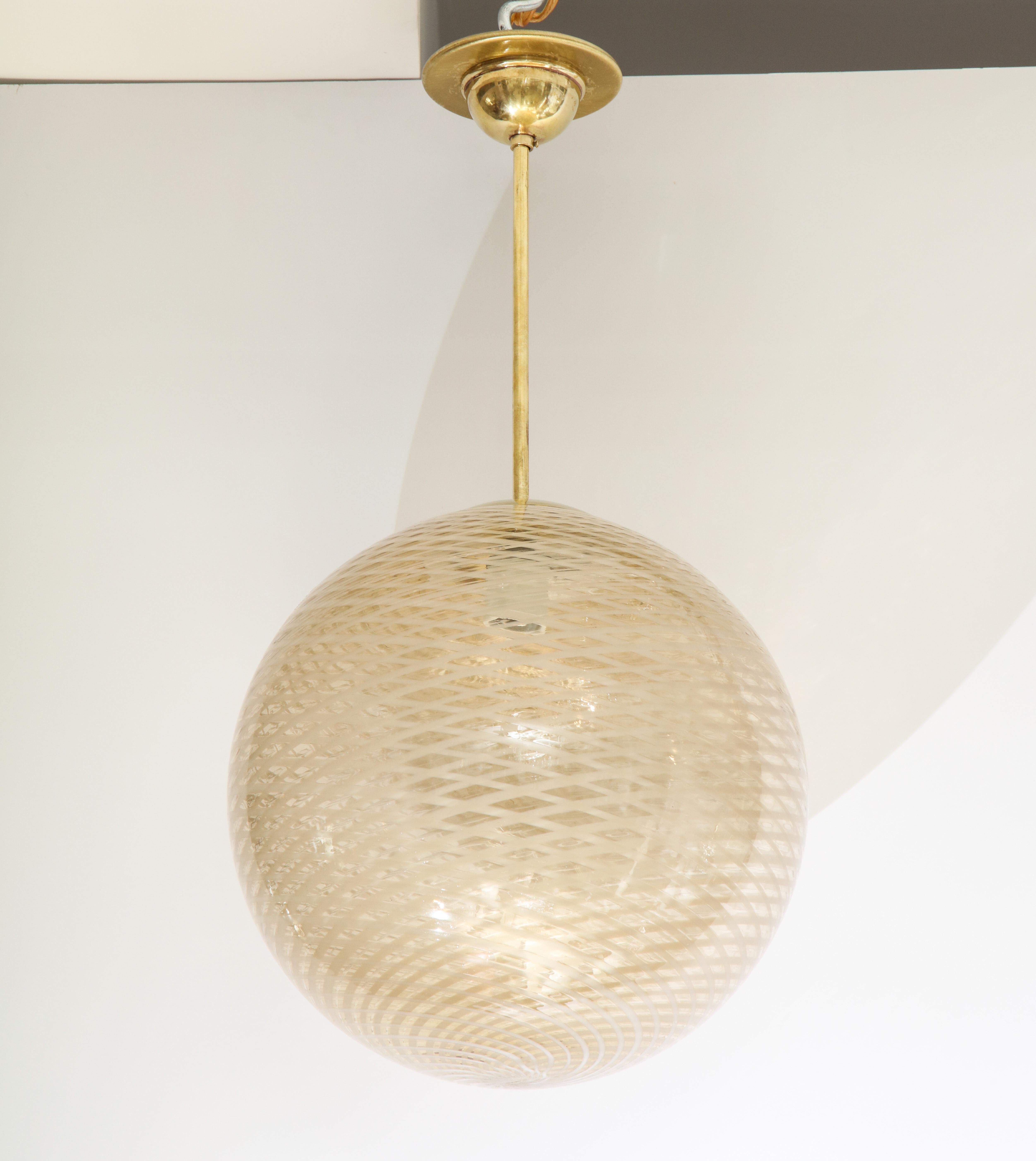 Venini early and rare 1930s stunning reticello glass globe chandelier in a beautiful and warm gold, cream and white hand blown glass; iconic swirl design with brass columnar support and canopy. All original. (Re-wired for USA standards). Attributed