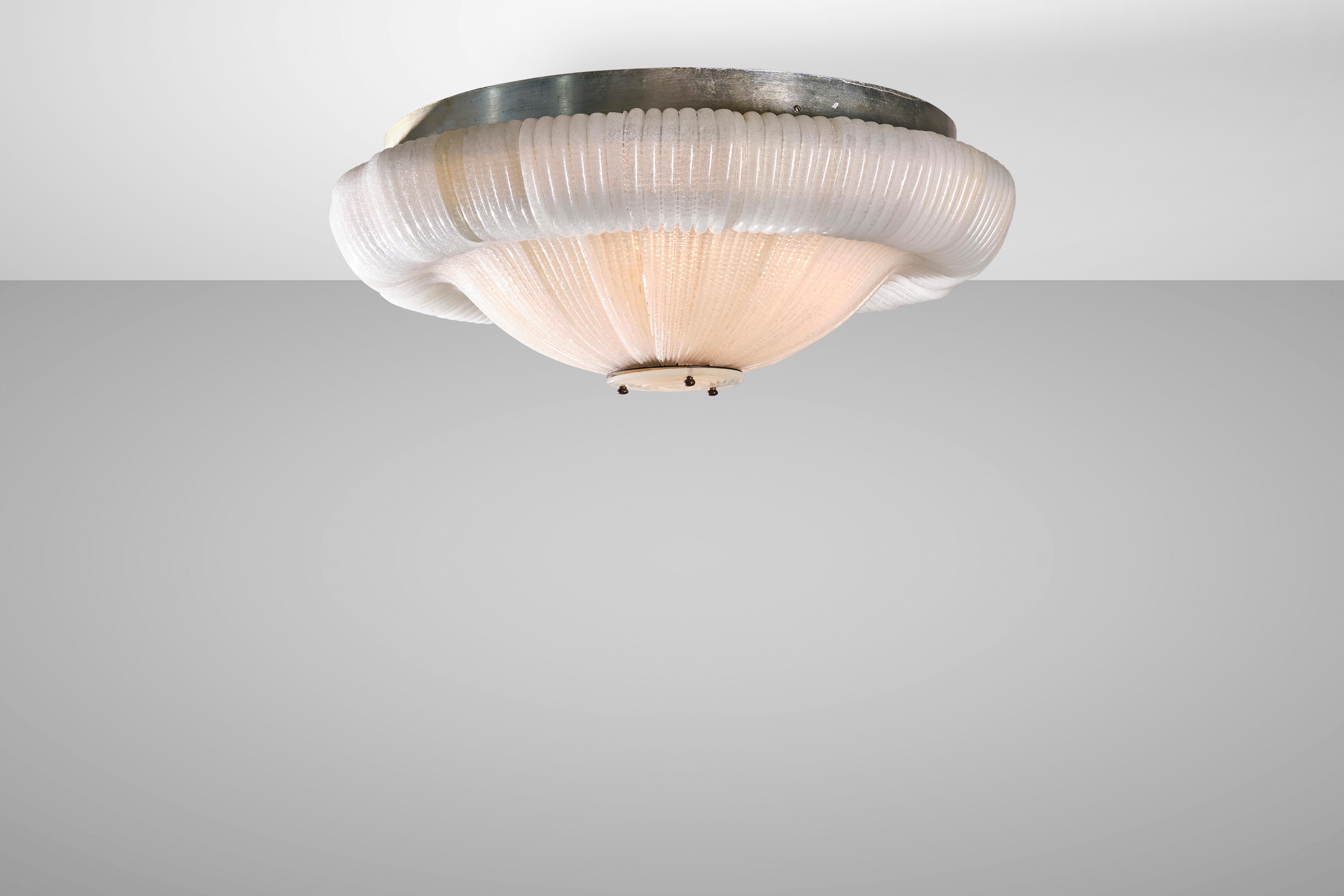 Elegant and timeless, Murano glass ceiling lamps are varied and diverse but each carries with it the aura of the wisdom of the lagoon's master glassmakers. This chandelier created by Venini in the 1940s is made of metal and brass with Cordonato