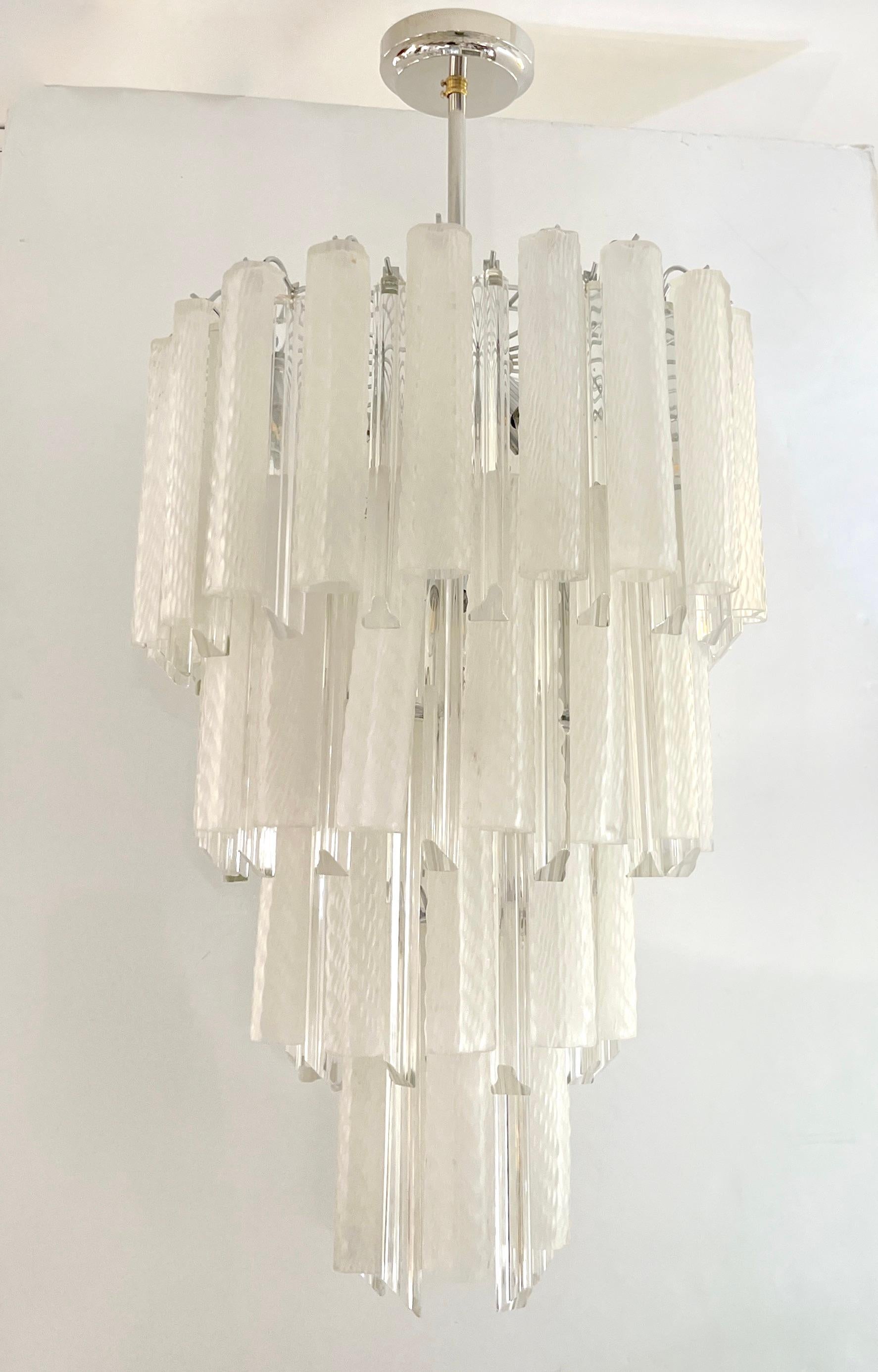 A pair is available - Midcentury design organic chandelier, entirely handcrafted in Italy by Venini. The chrome color metal structure supports cylindrical glass tubes of waved triangular triedri shape, in sophisticated textured blown Murano glass