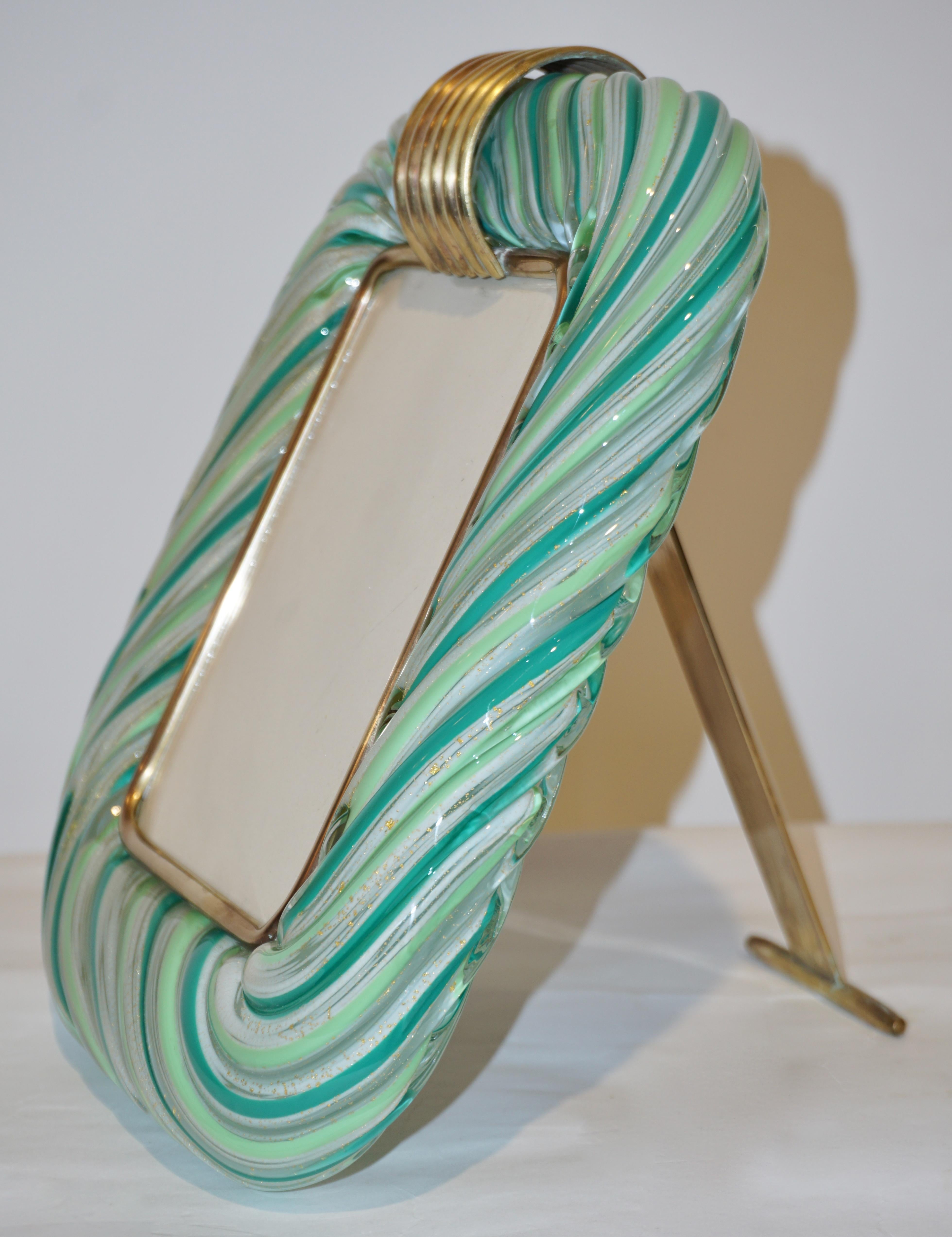 Venetian modern design picture frame in thick blown clear Murano glass by Venini, signed piece. The elegant decoration of the highest quality, with precious gold dust and two-tone intertwined apple green and sea green filigrana with an underlayer of