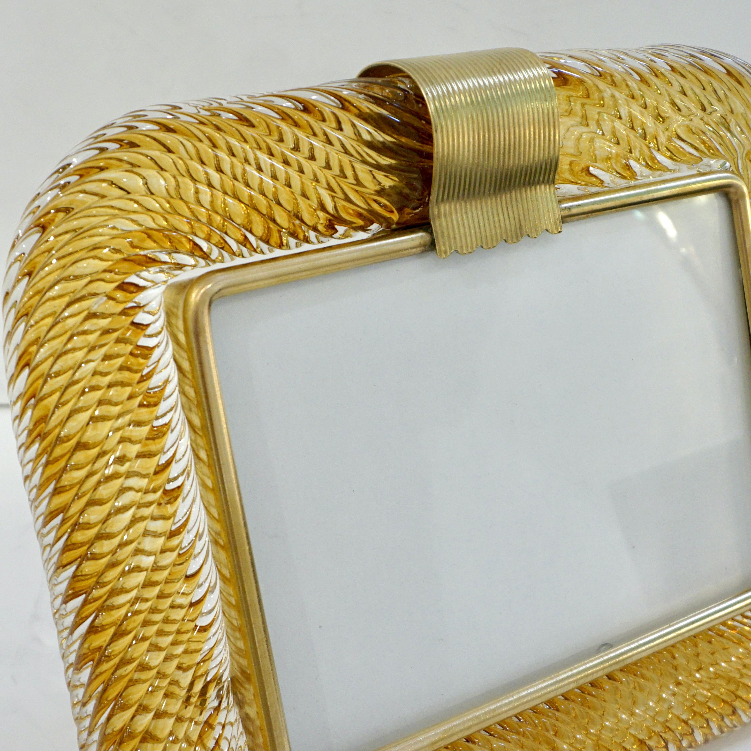 A sophisticated Venetian modern design horizontal picture frame in thick blown crystal clear Murano glass decorated with a Sommerso inset ribbon in luscious honey amber color, by Venini, signed piece. The elegant texture of the tightly twisted glass