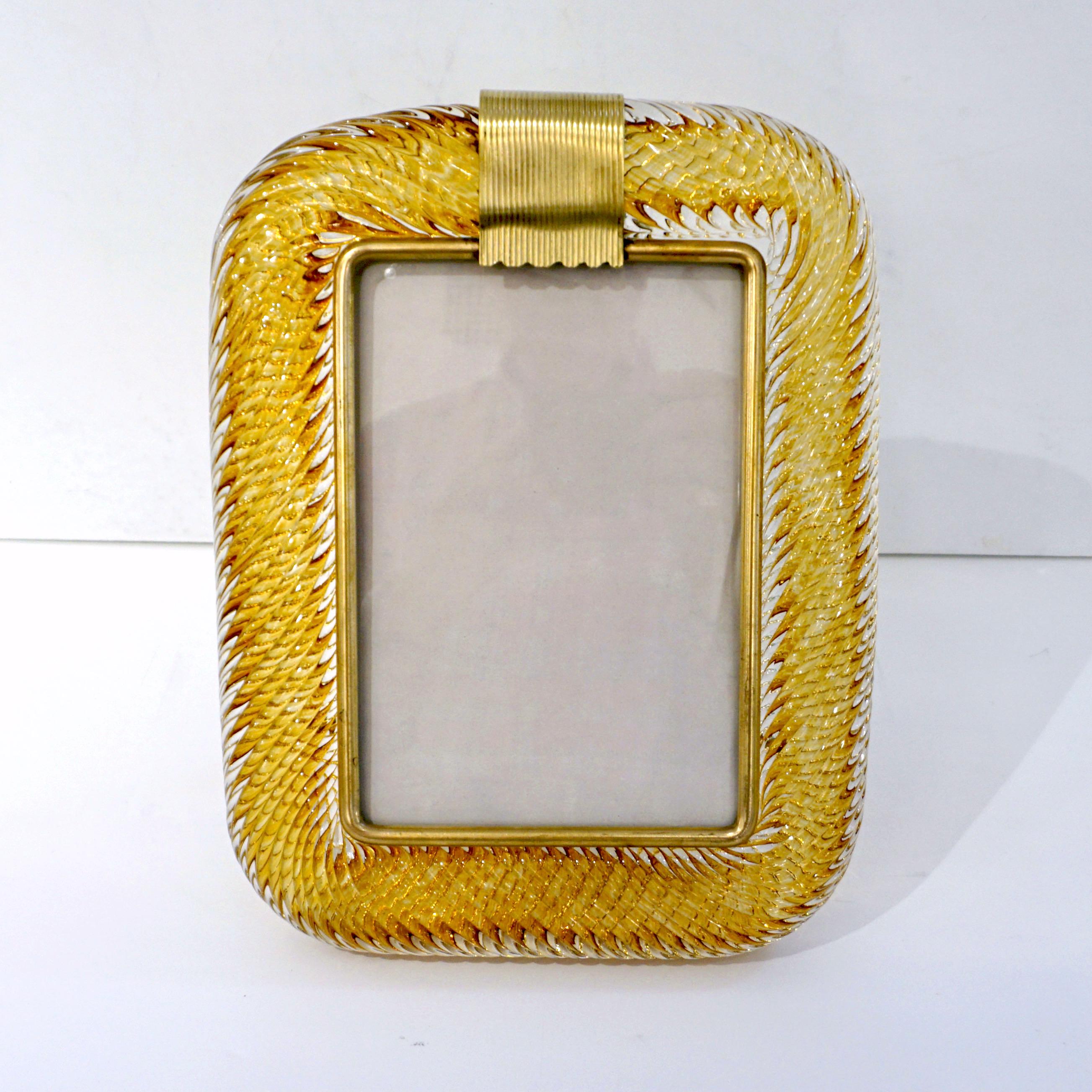 A sophisticated Venetian modern design vertical picture frame in thick blown crystal clear Murano glass decorated with a Sommerso inset ribbon in luscious honey amber color, by Venini, signed piece. The elegant texture of the tightly twisted glass